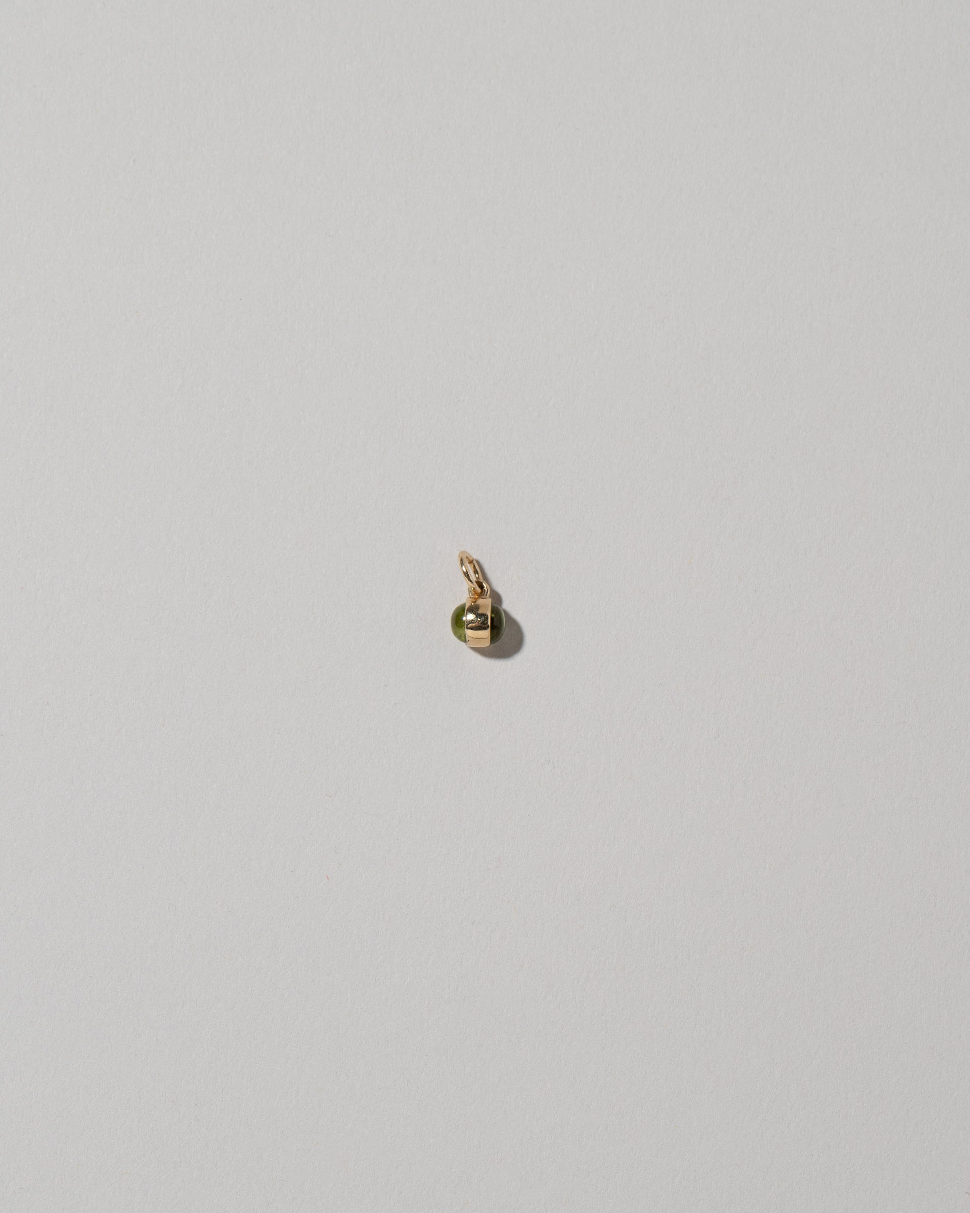 Samples & Imperfects 14k Yellow Gold Peridot Birthstone Charm on light color background.