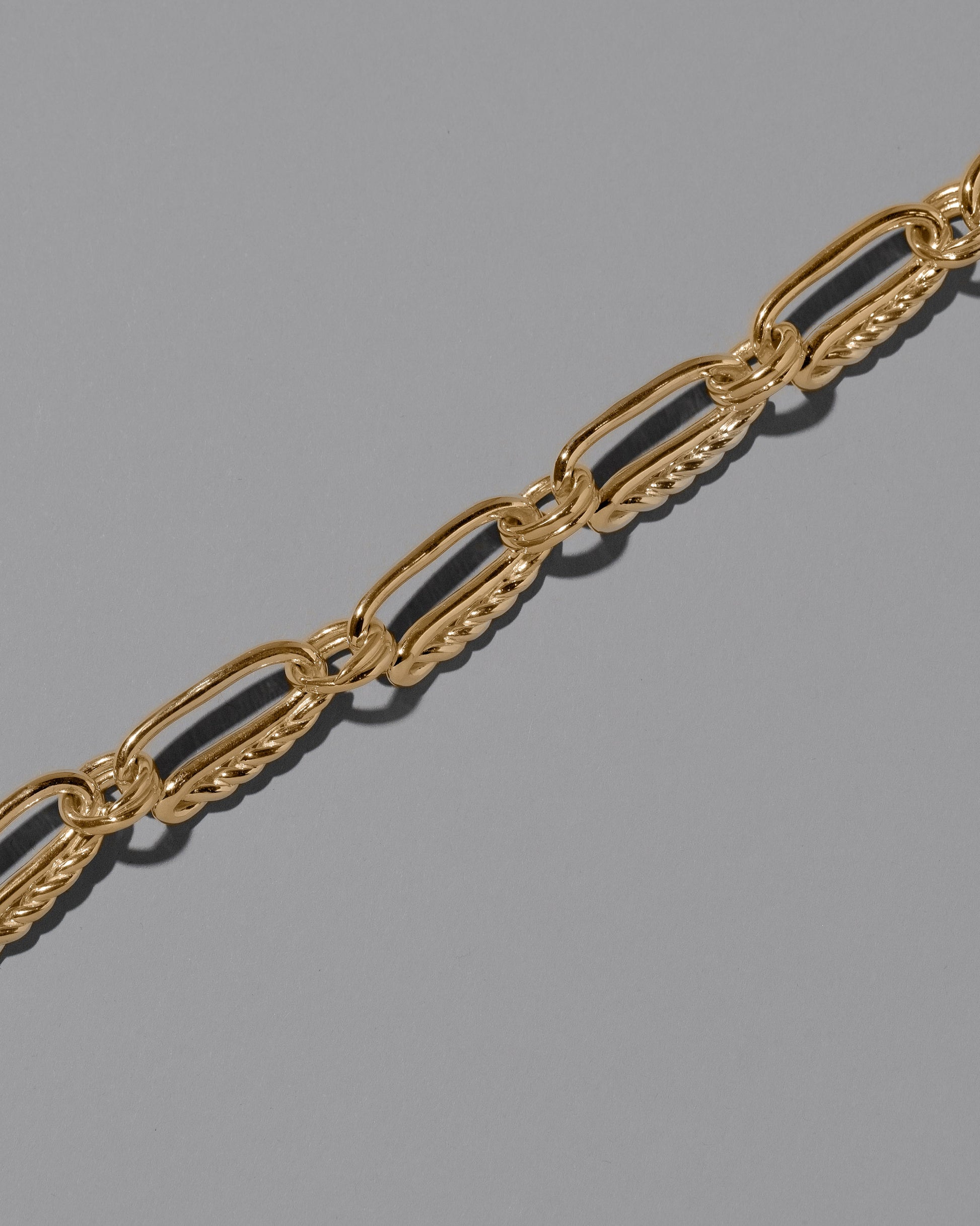 Closeup details of the CRZM 22k Gold Ophiolite Bracelet on light color background.