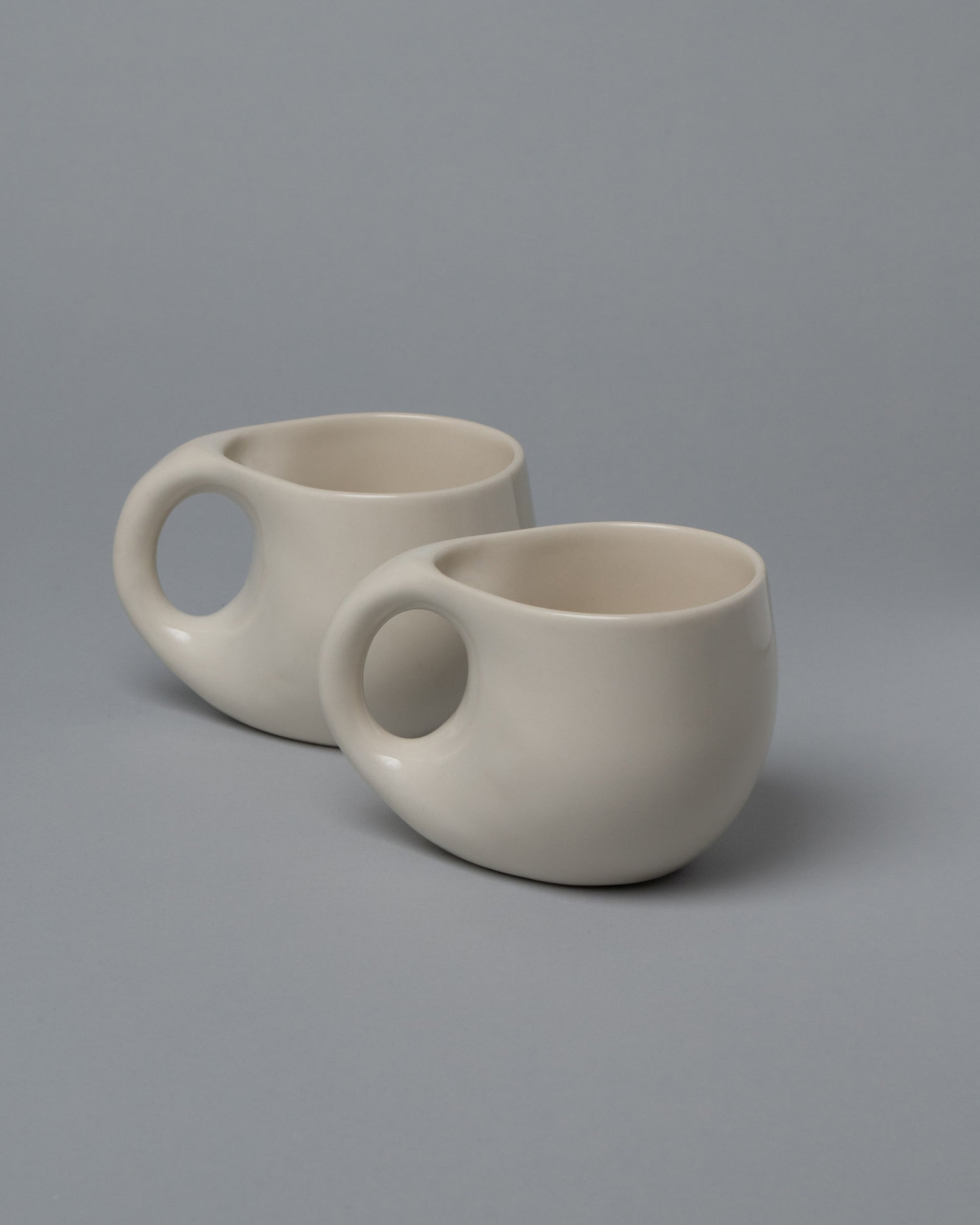 Closeup view of half of the Dust and Form Mugs Set, including the Large Cream Comfort Mugs on light color background.