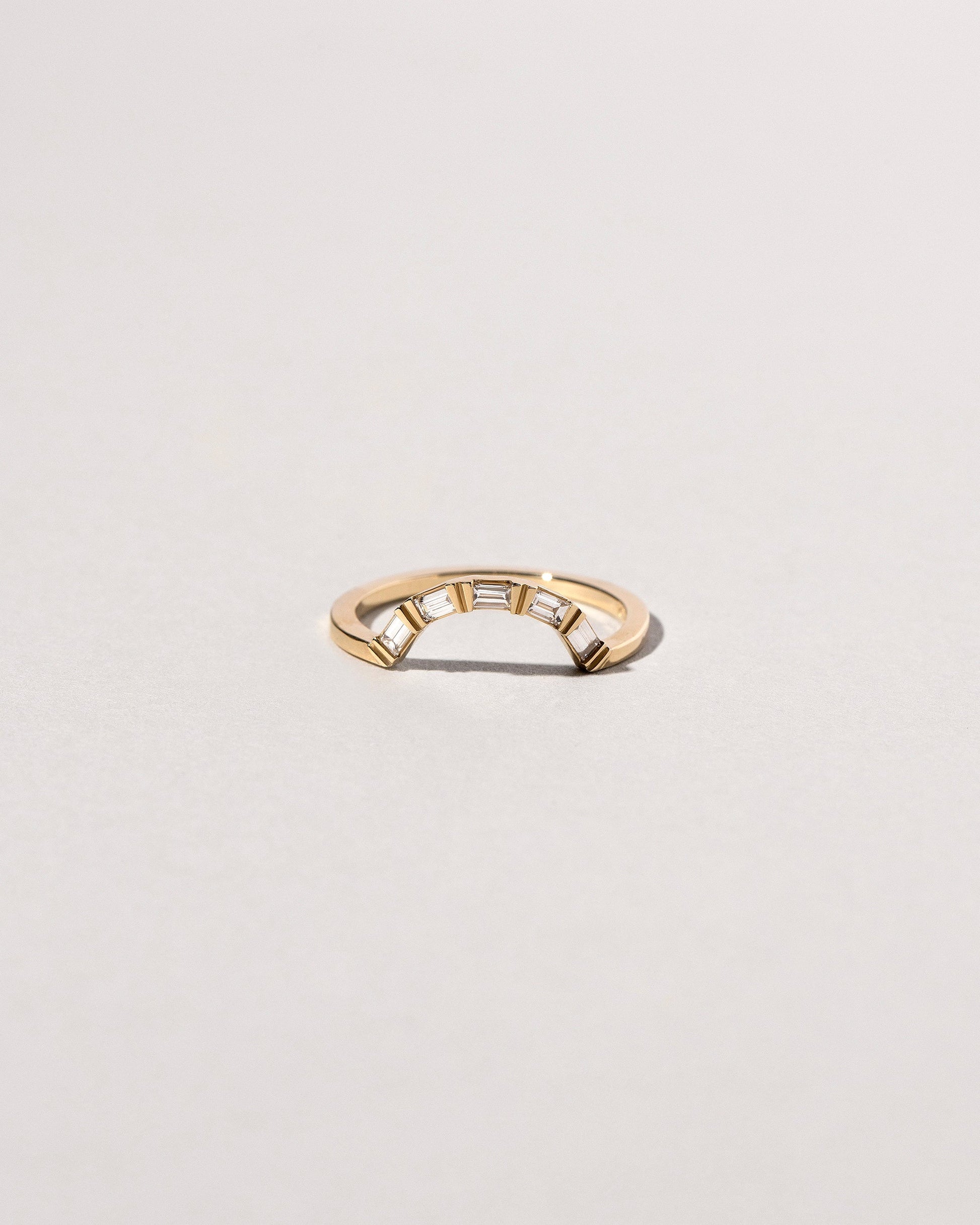 Gold Baguette Curve Band on light color background.