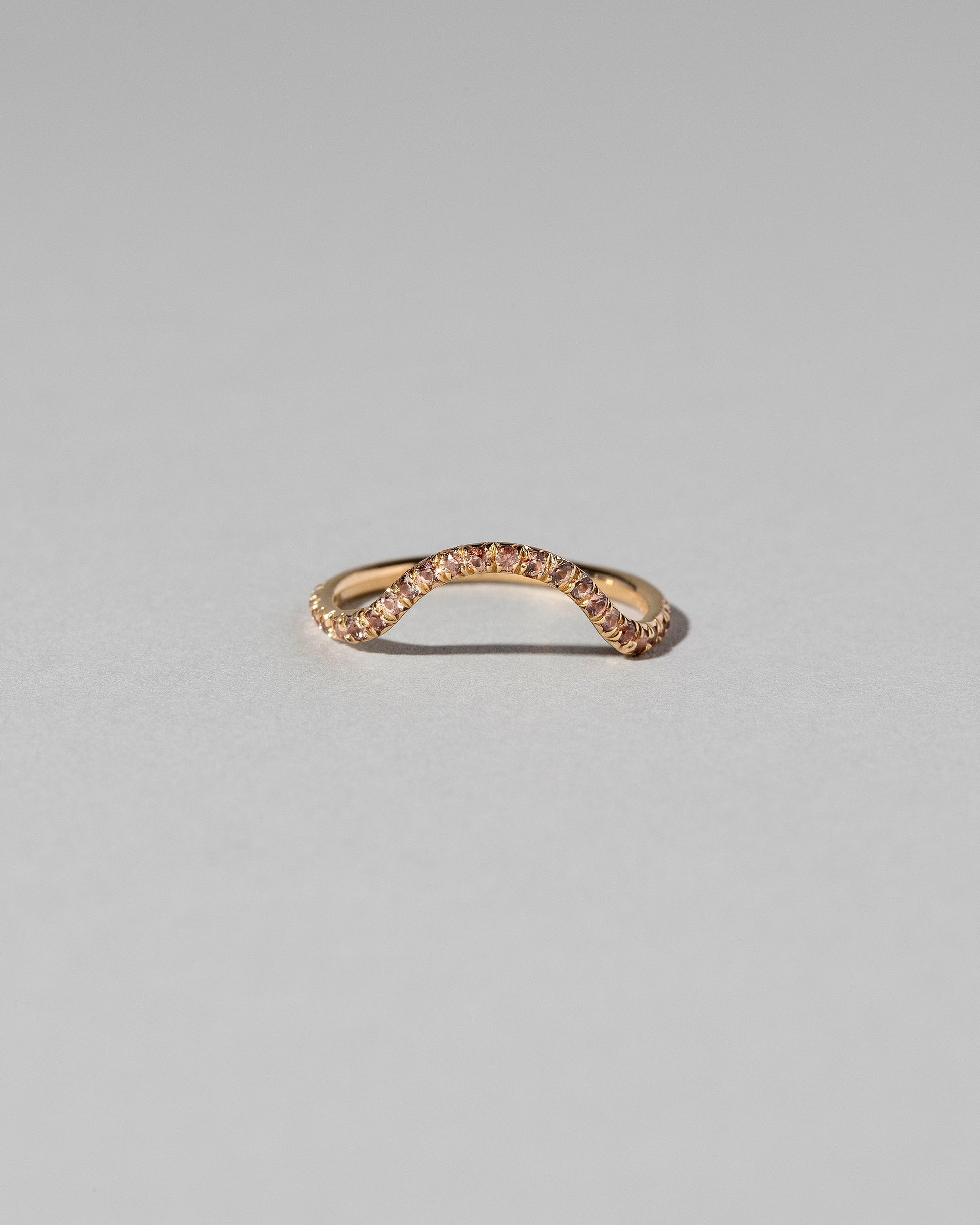 Gold Pavé Peach Sapphire Curve Band on light color background.