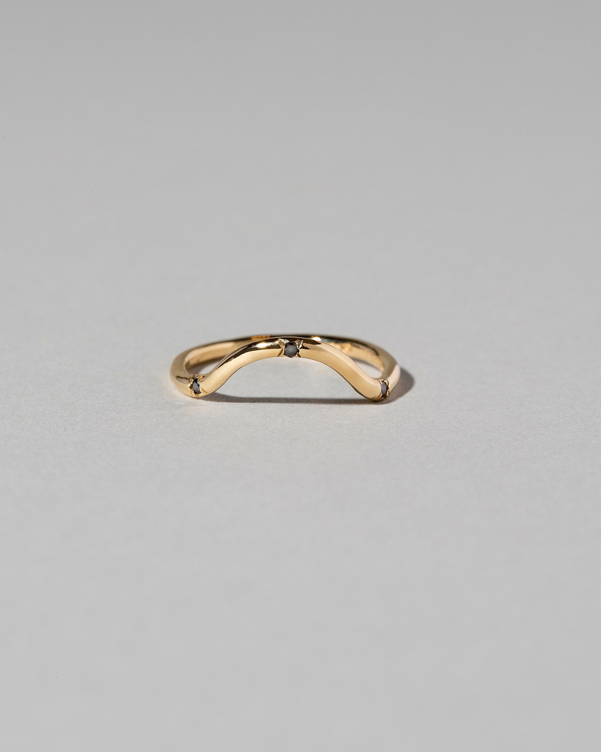 Gold Black Diamond Three Stone Curve Band on light color background.