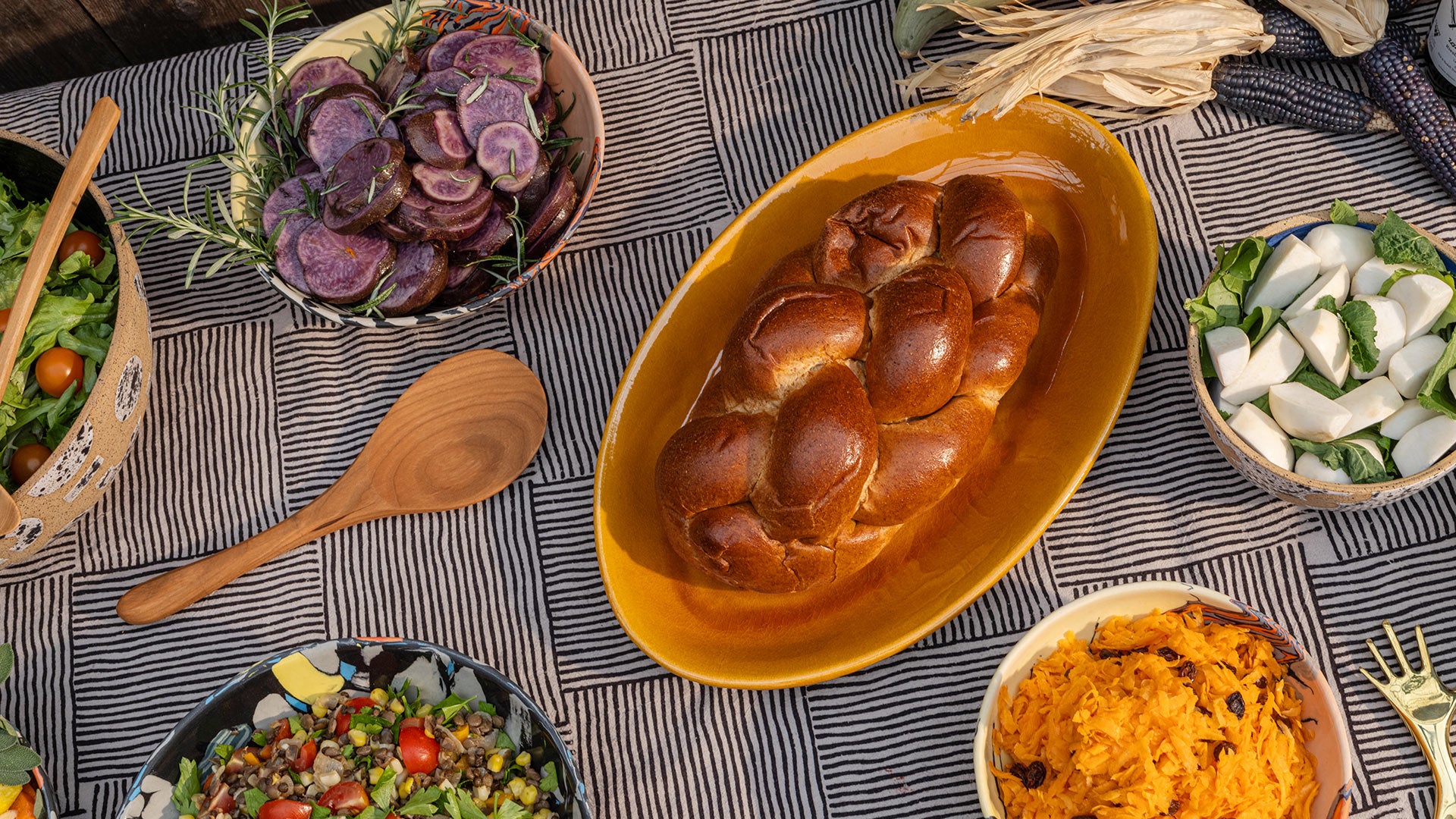 Editorial photo of bowls and platters filled with food on a black and white patterned background. 