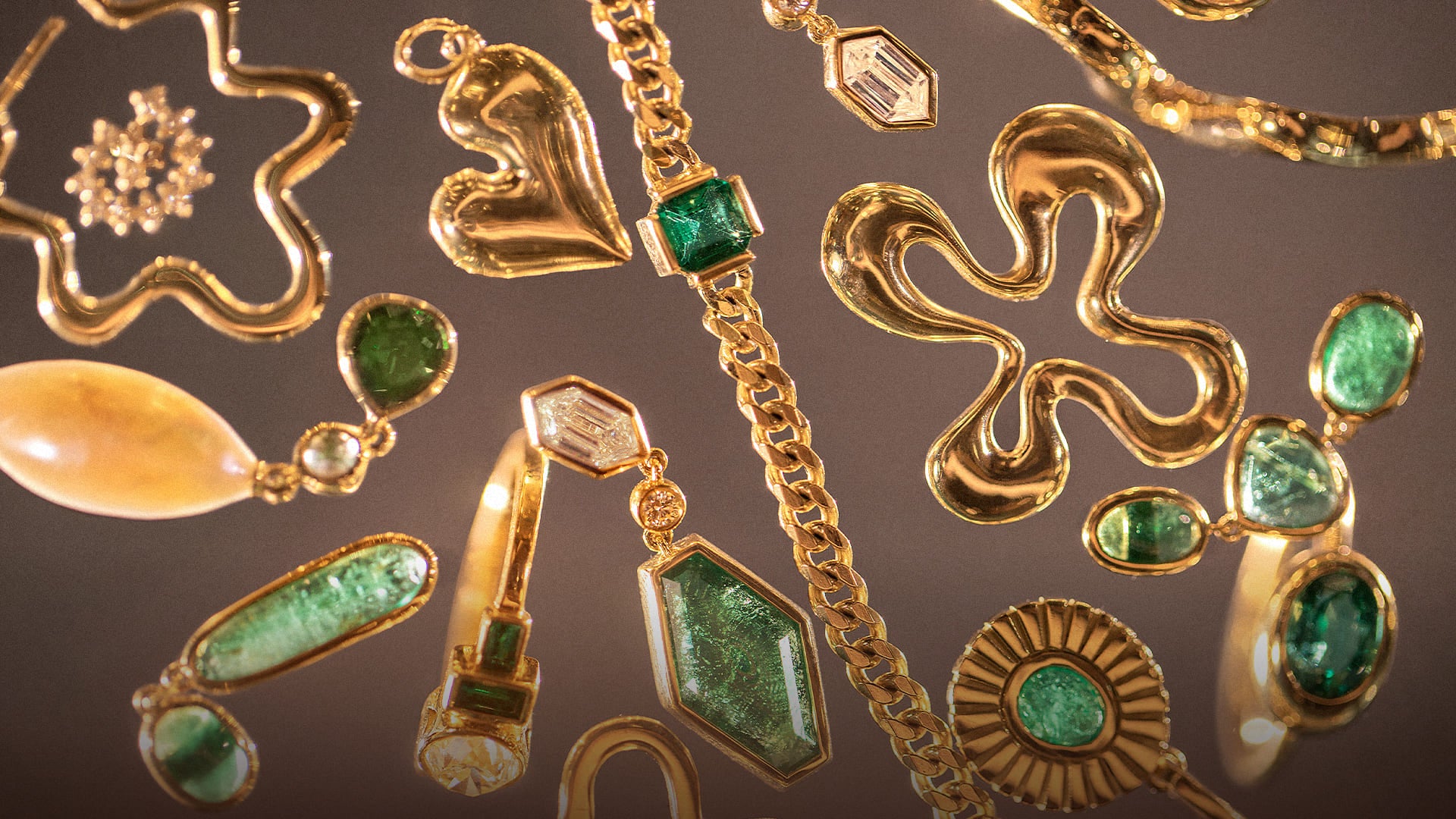 Photo of mixed Mociun, gold, emerald and diamond jewelry on a mauve color background. 