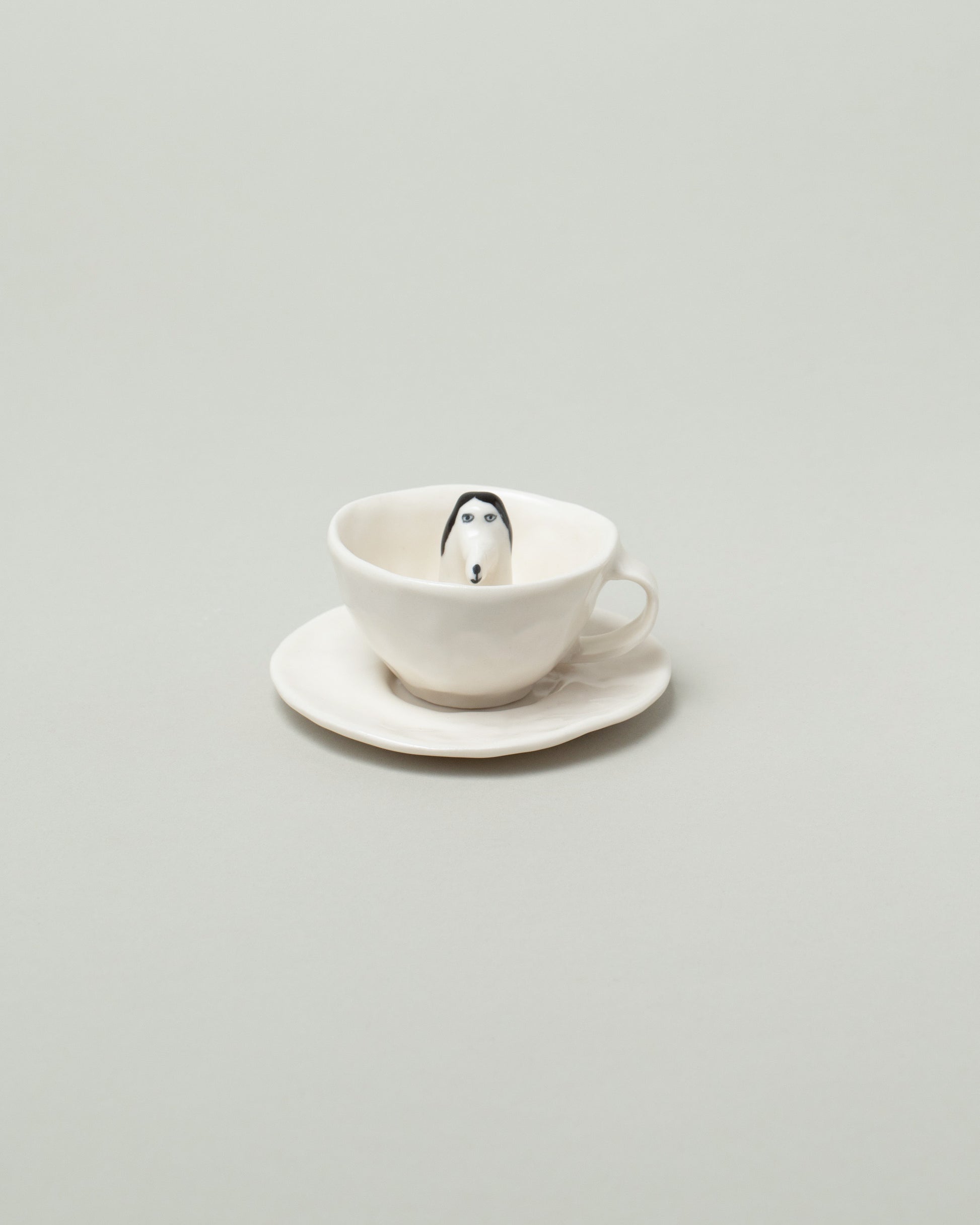 Eleonor Boström Espresso Dog Cup & Saucer on light color background.