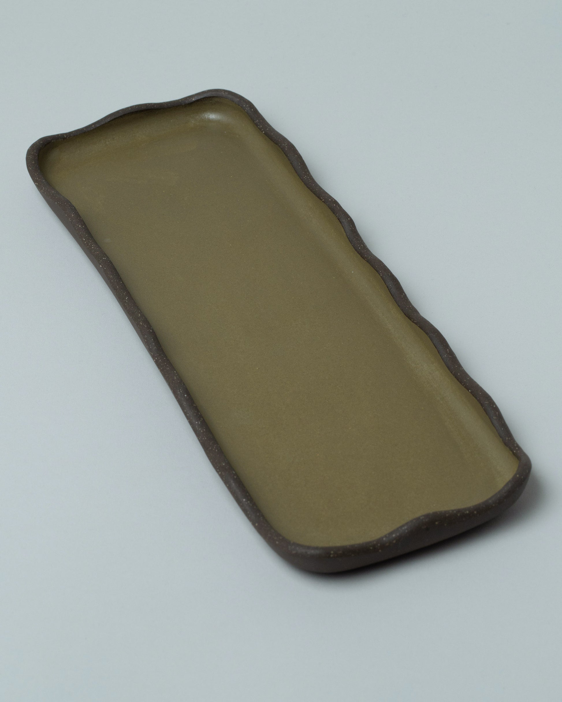 Emris Dark Stoneware Scalloped Tray on light color background.