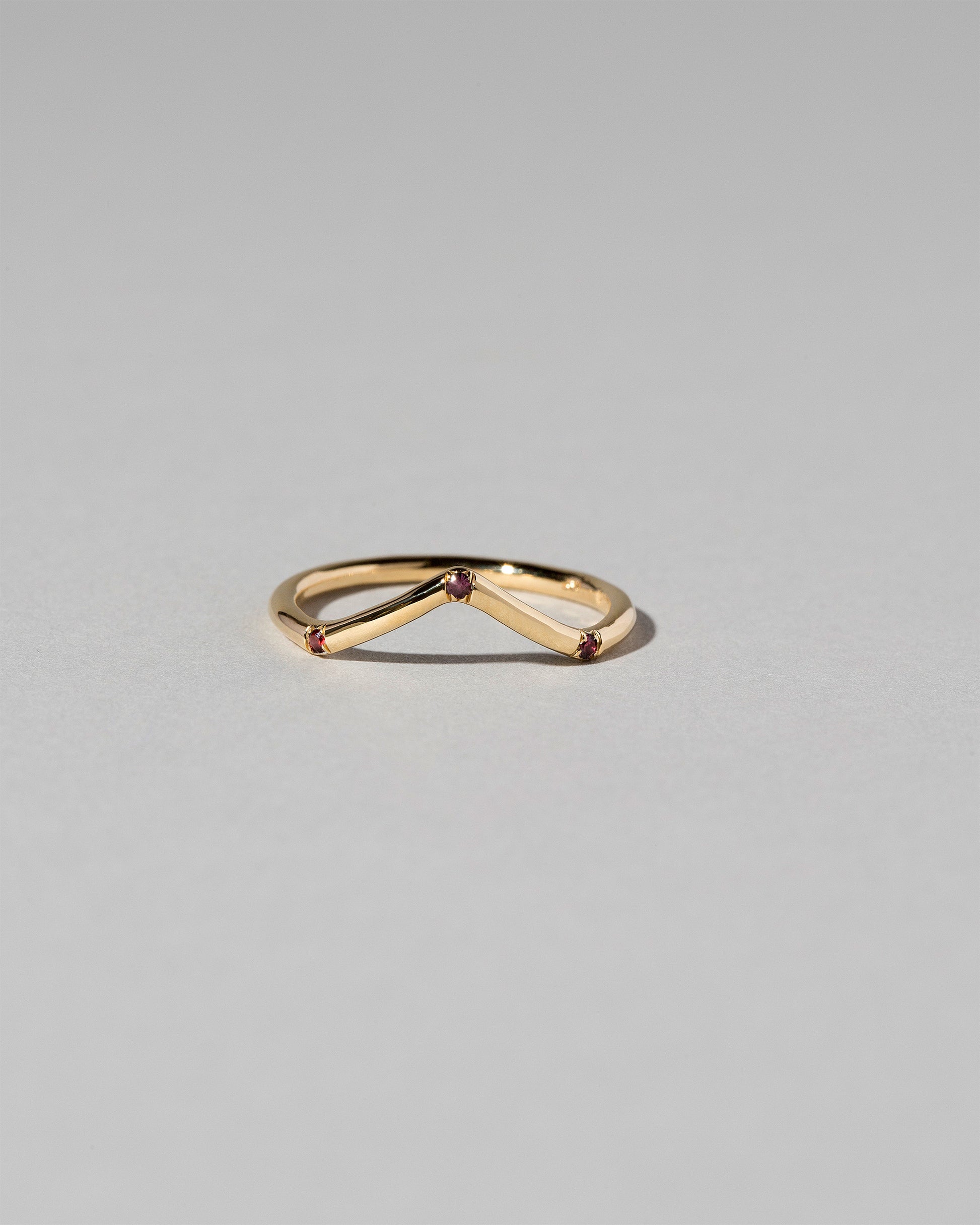 Gold Three Stone Garnet High Peak Band on light color background.