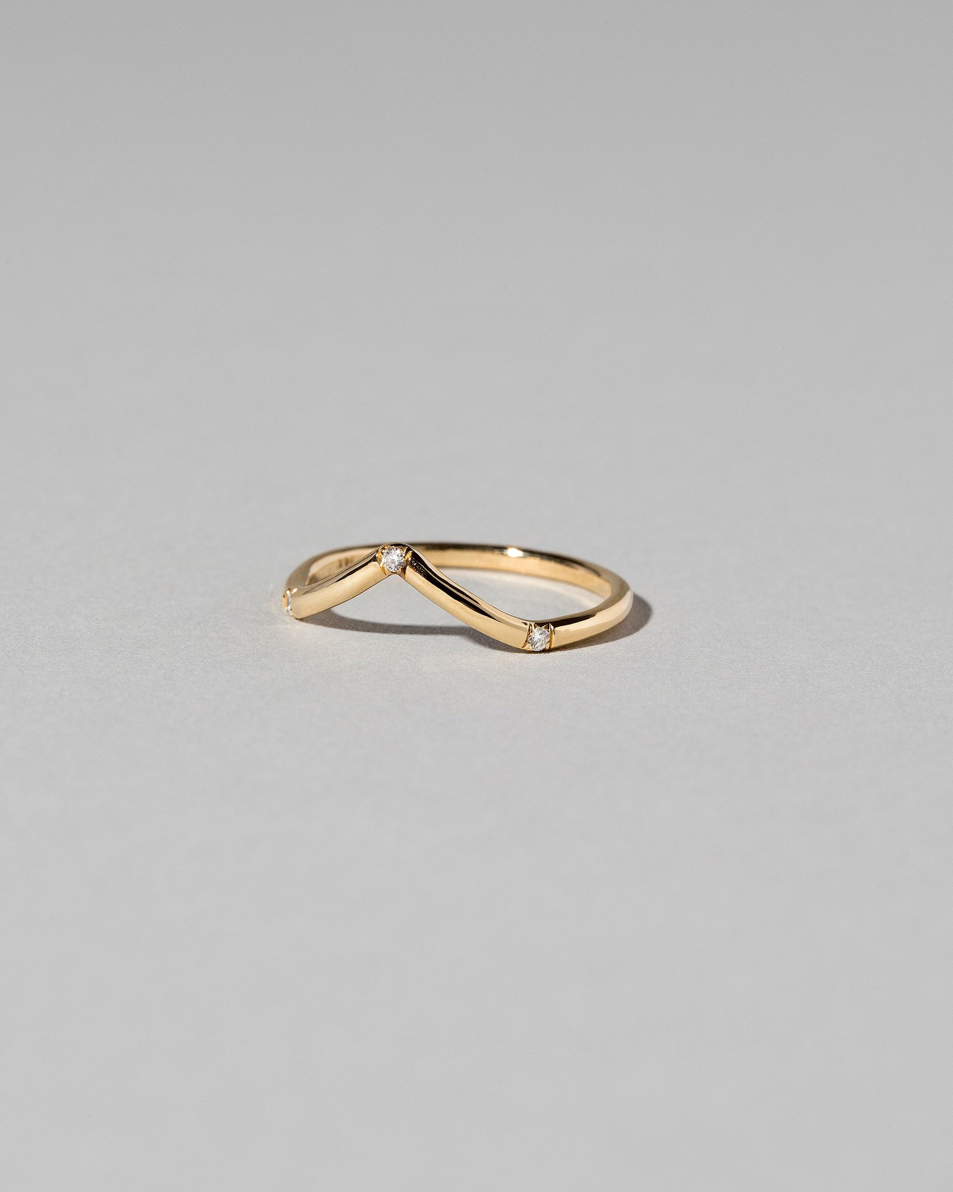 View from the side of the Gold Three Stone White Diamond High Peak Band on light color background.