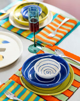 Styled image featuring the Casa Veronica Leche and Azul Mini Vida Bowls, Sol and Azul Vida Bowls, and Leche and Sol Vida Plates, a Fazeek Teal Wave Flute Set and E.E. Ceramics Smiley Serving Platter.