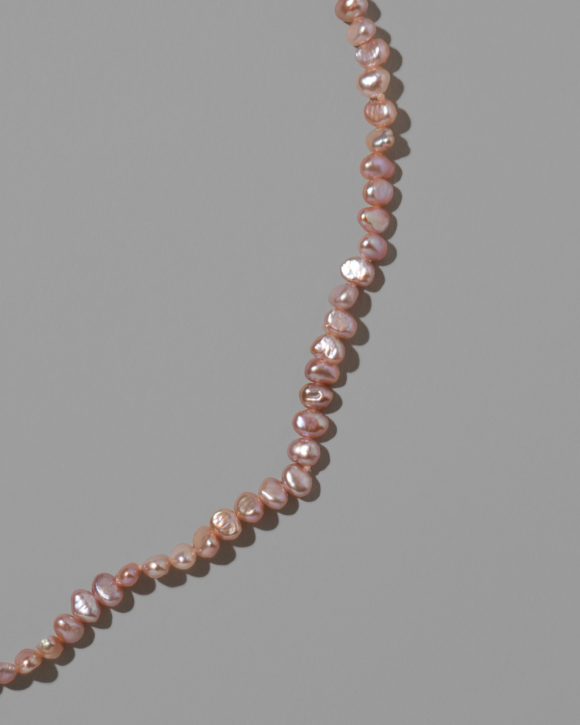 Closeup details of the Pink Peony Baroque Pearl Necklace on light color background.