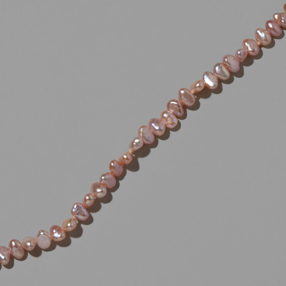 product_details::Closeup details of the Pink Peony Baroque Pearl Bracelet on light color background.