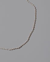 Closeup details of the White Oval Pearl Necklace on light color background.