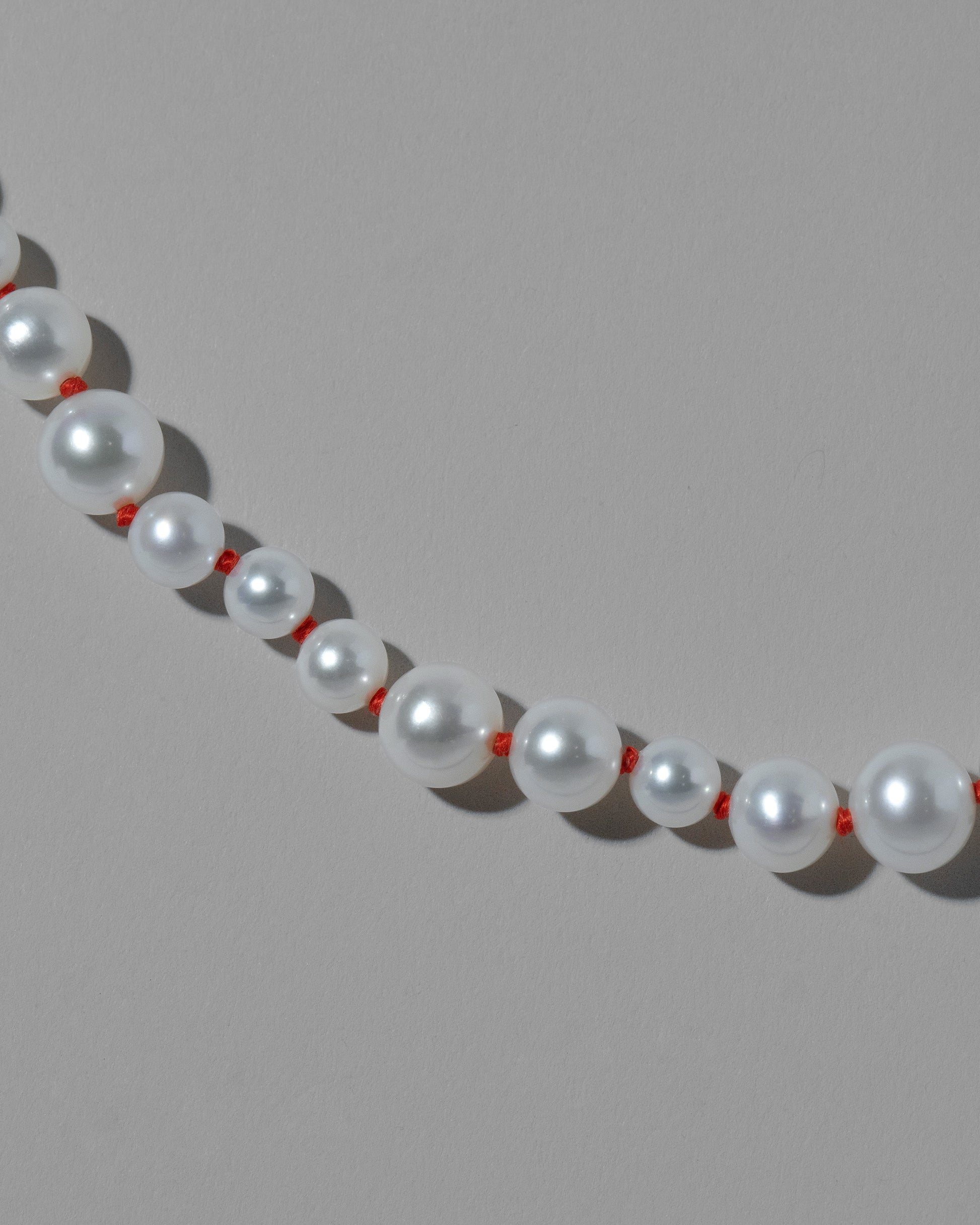 Closeup details of the Cardinal Red Thread Bubble Pearl Bracelet on light color background.