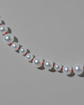 Closeup details of the Cardinal Red Thread Bubble Pearl Necklace on light color background.