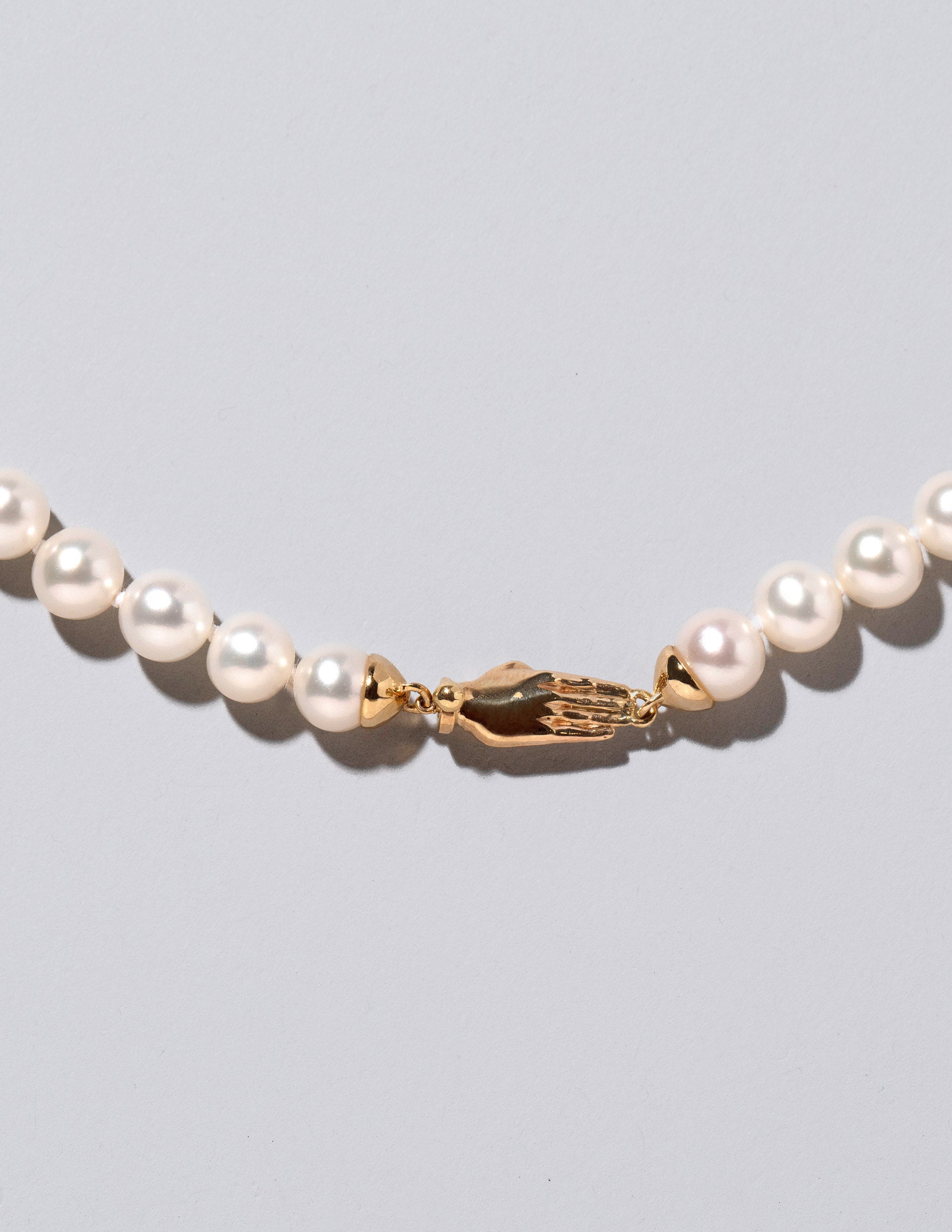 Closeup detail of the White Pearl & Yellow Gold Union Pearl Necklace on light color background.