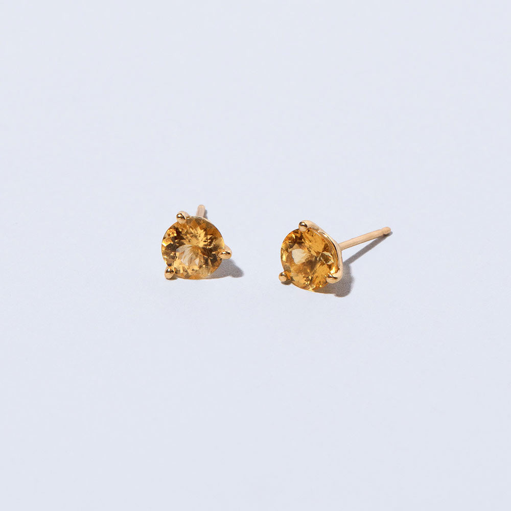 product_details::Closeup details of the Super Yellow Beryl Martini Stud Earrings on light color background.