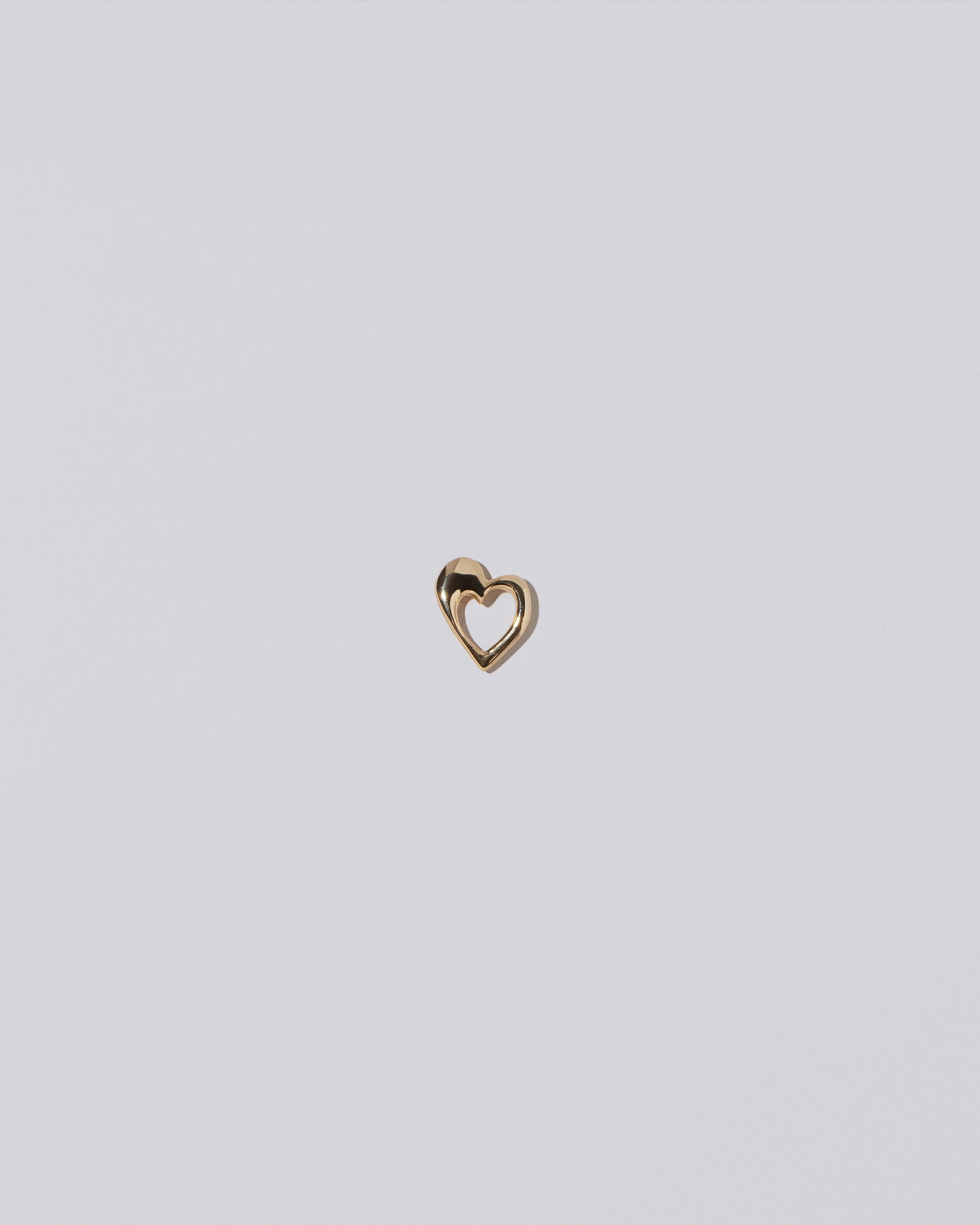 Gold Open Thousand & One Night Heart Charm on light color background.