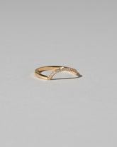 View from the side of the Gold Pavé White Diamond Left Slump Band on light color background.