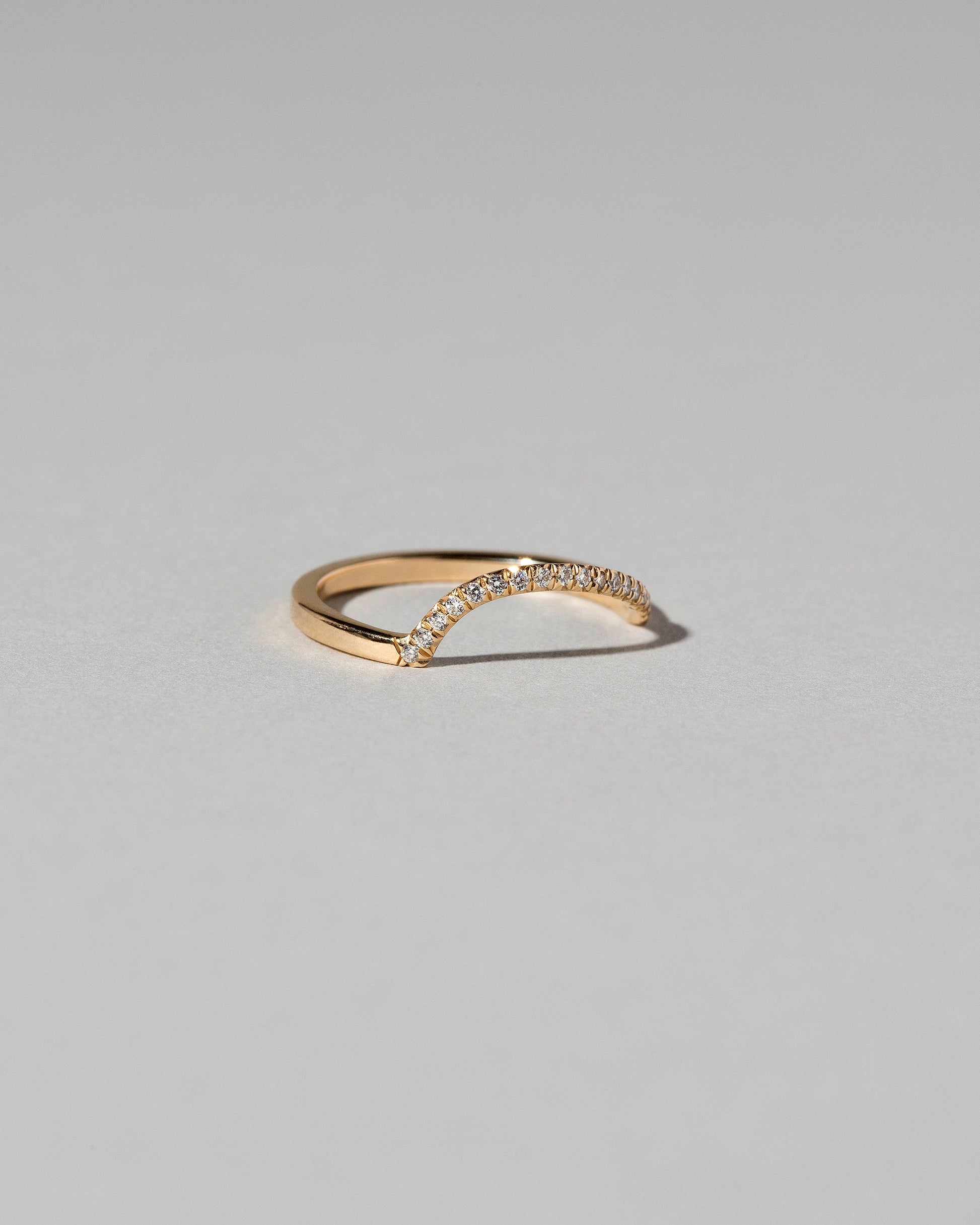 View from the side of the Gold Pavé White Diamond Left Slump Band on light color background.