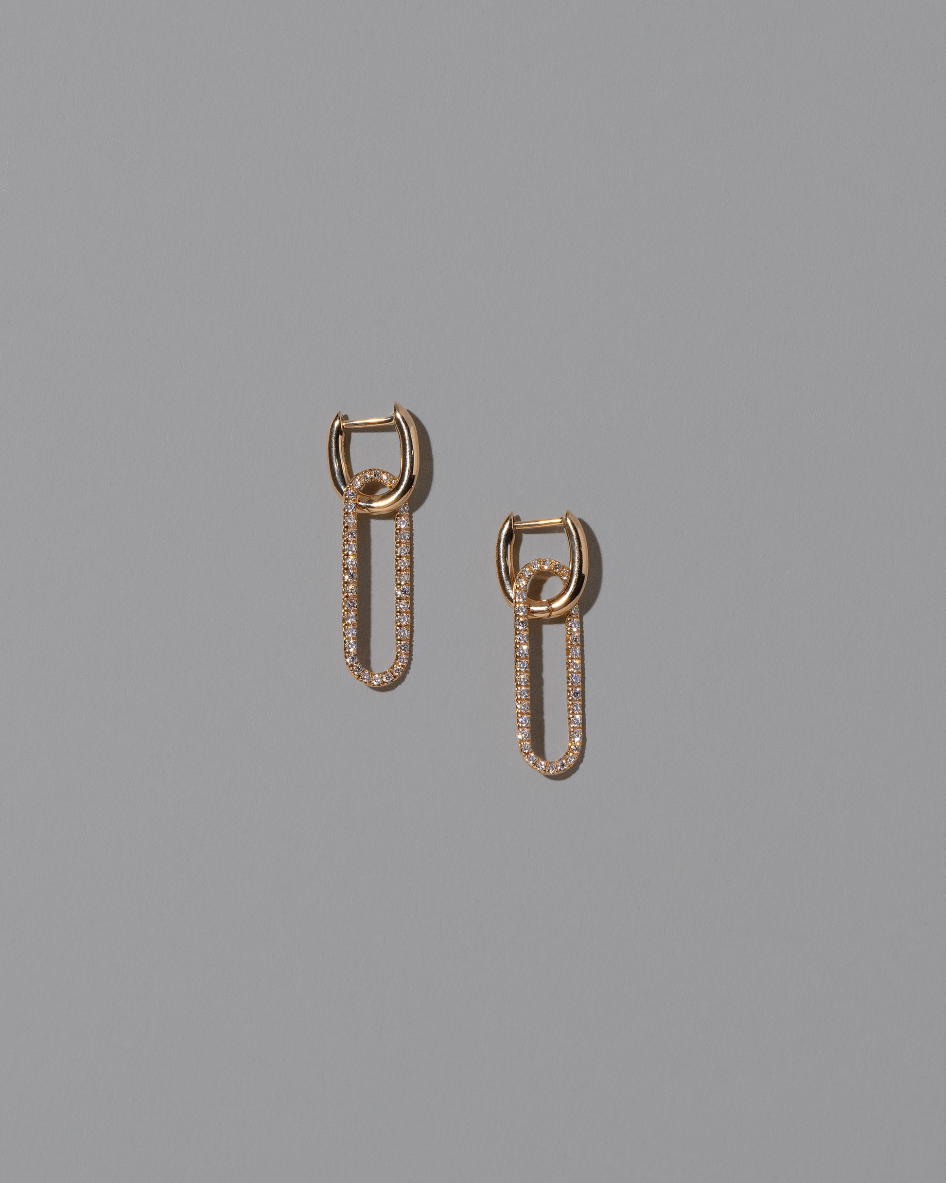 Pavé Link Huggie Hoop Earrings on light color background.