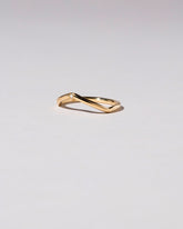 View from the side of the Gold Three Stone White Diamond Low Peak Band on light color background.