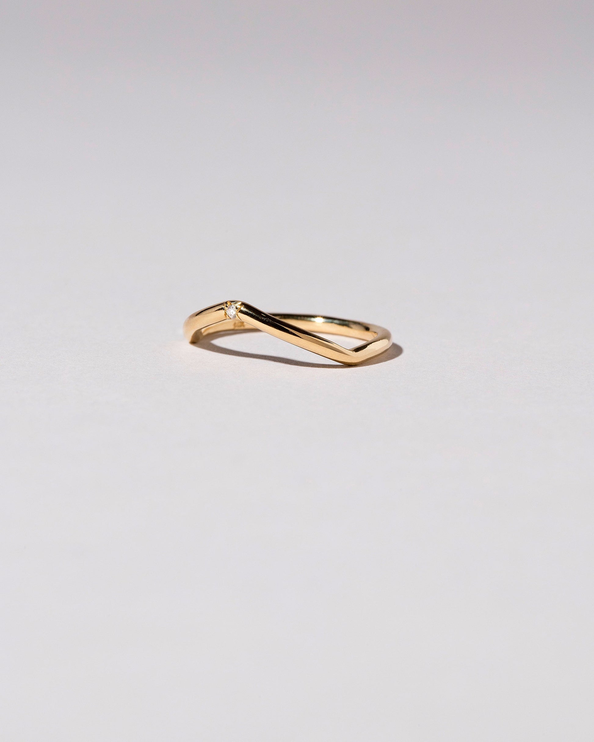 View from the side of the Gold Three Stone White Diamond Low Peak Band on light color background.