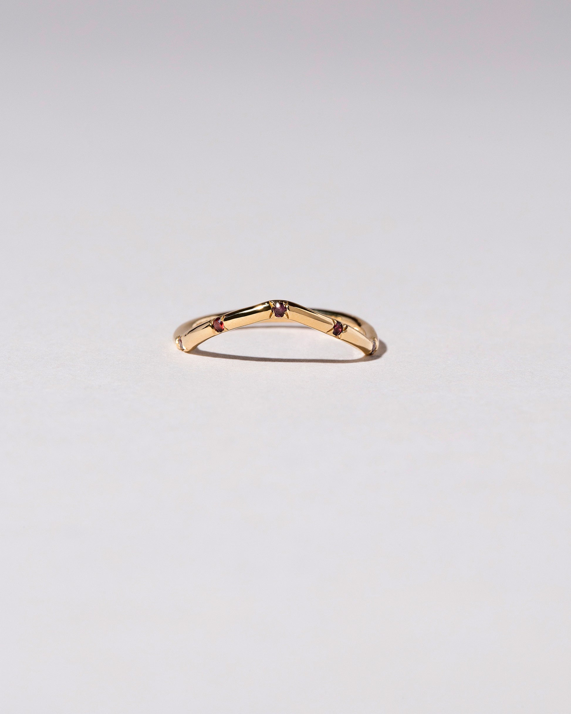 Gold Five Stone Garnet Low Peak Band on light color background.