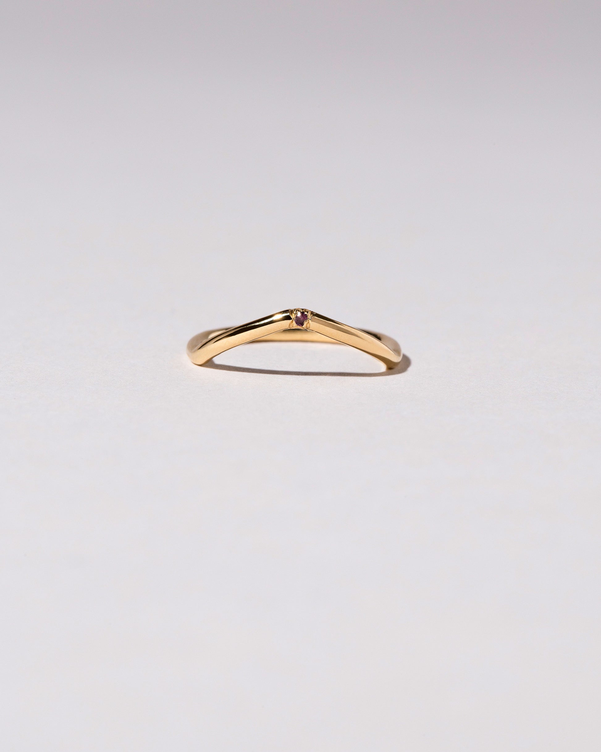 Gold Single Stone Garnet Low Peak Band on light color background.