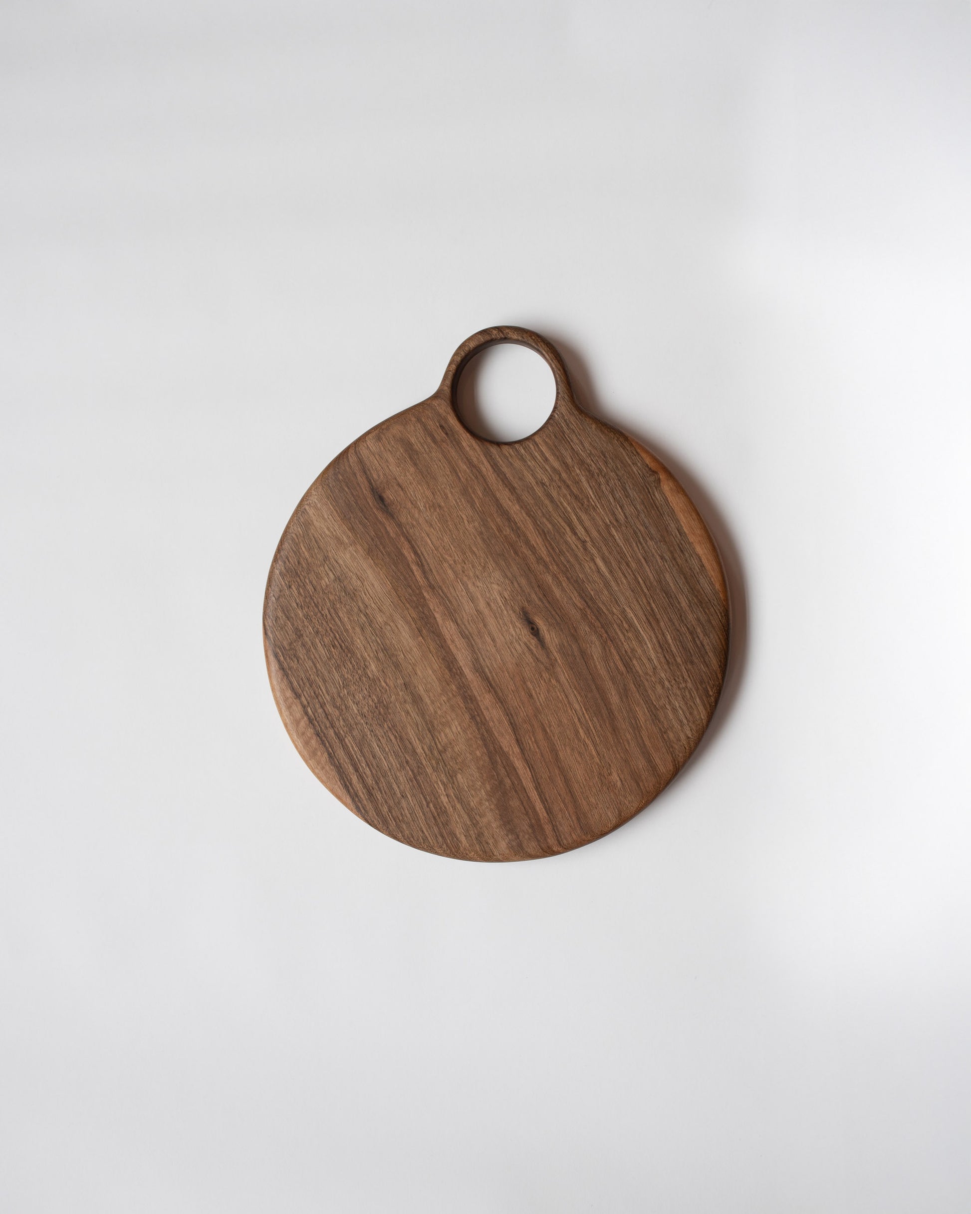 Lucas Castex No. 10 Hand-Carved Walnut Wood Serving Board on light color background.
