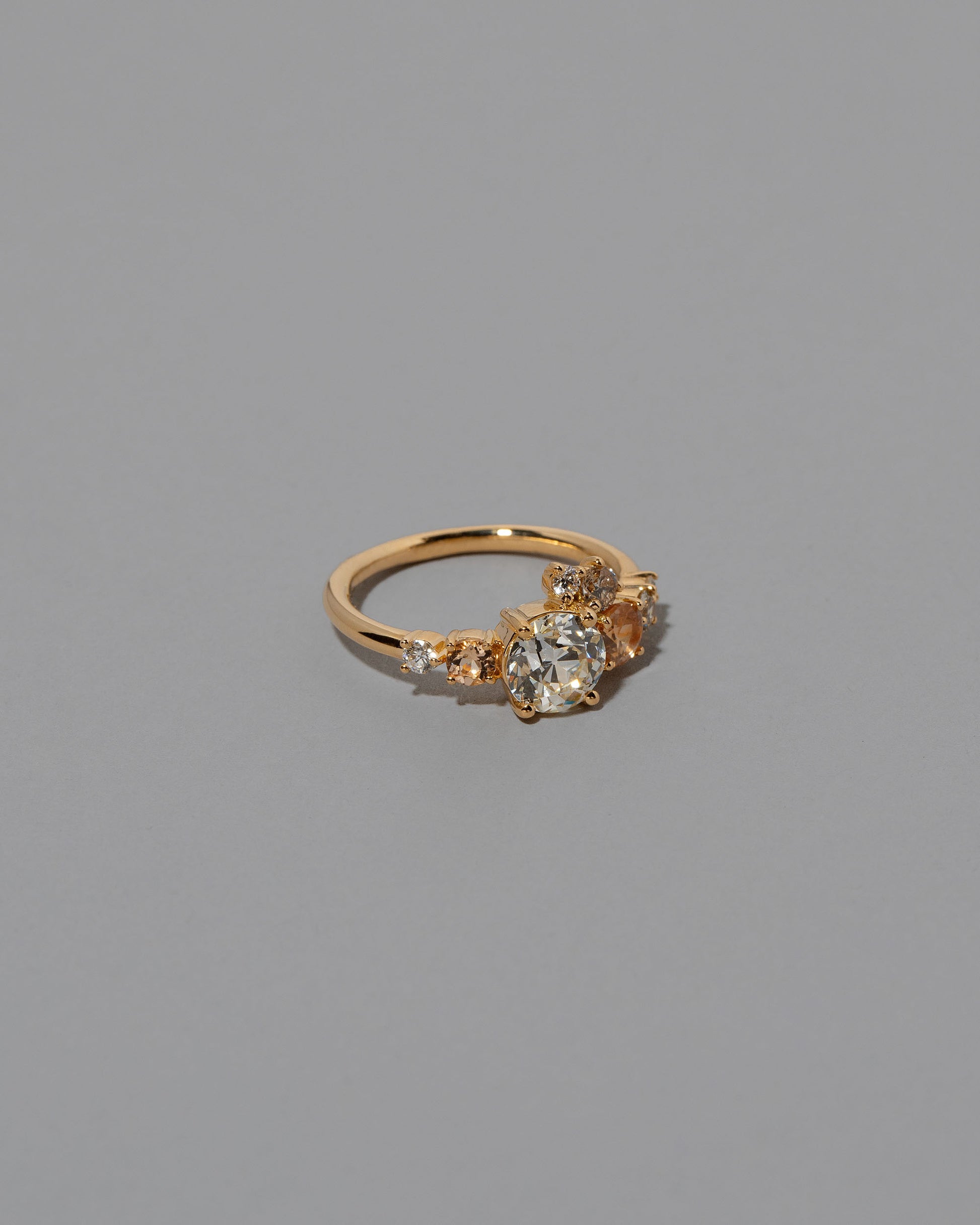 View from the side of the Peach Sapphire & Diamonds Luna Ring on light color background.