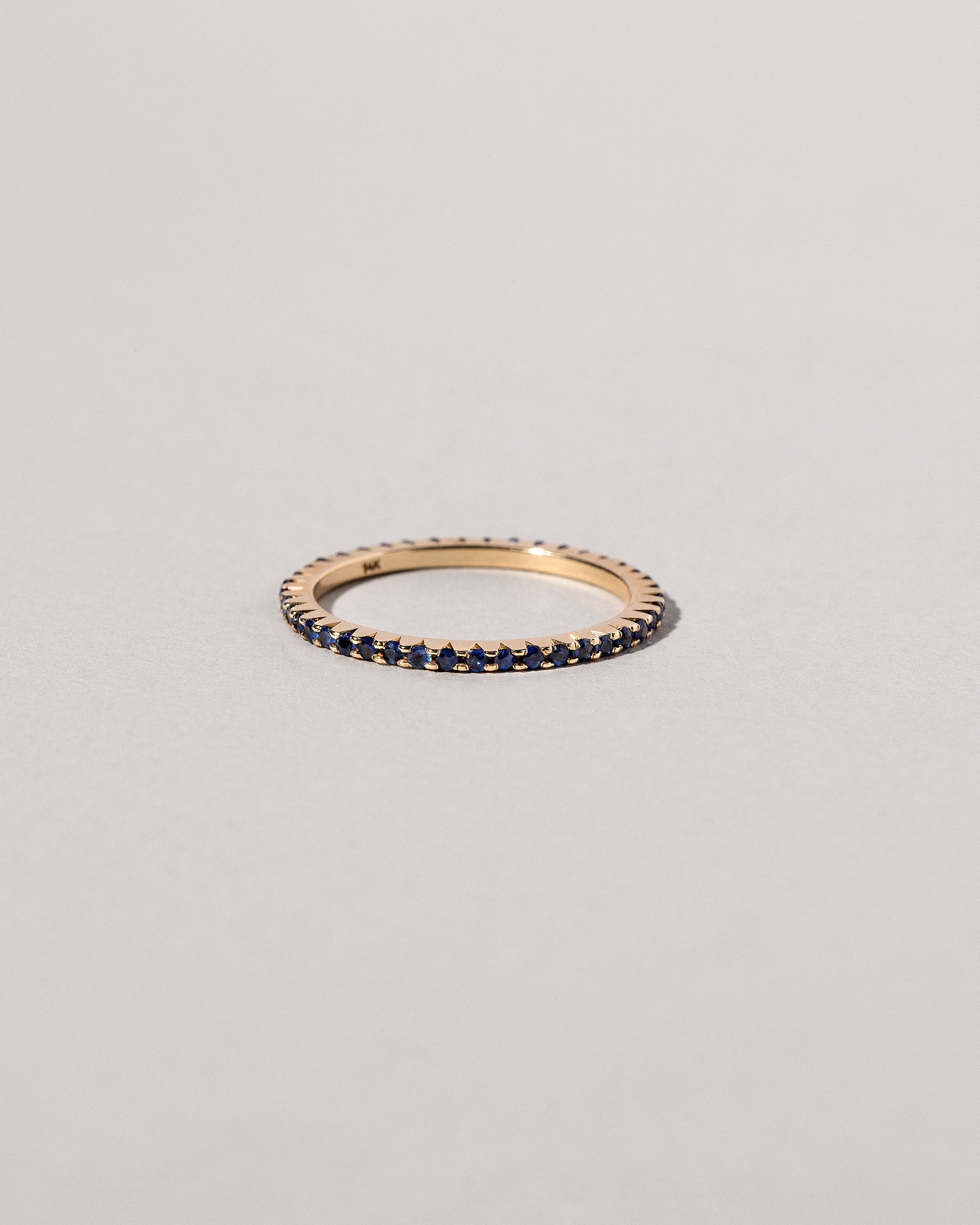 Gold Blue Sapphire Gear Edge Band on light color background.