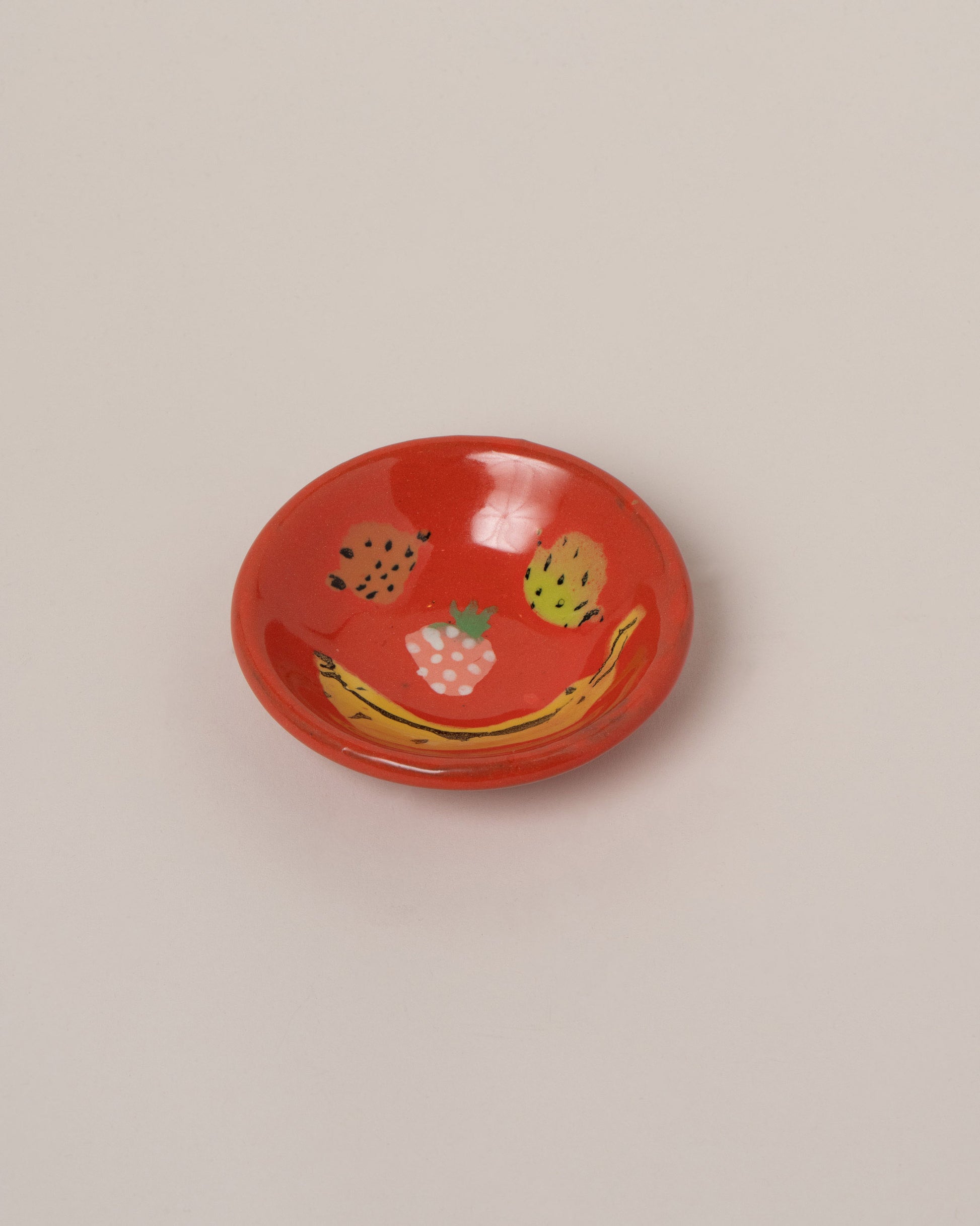 Maggie Boyd Red Fruit Face Banana Smile Dish on light color background.