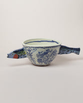 Maggie Boyd Sardine Swimming Through Delftware Bowl on light color background.