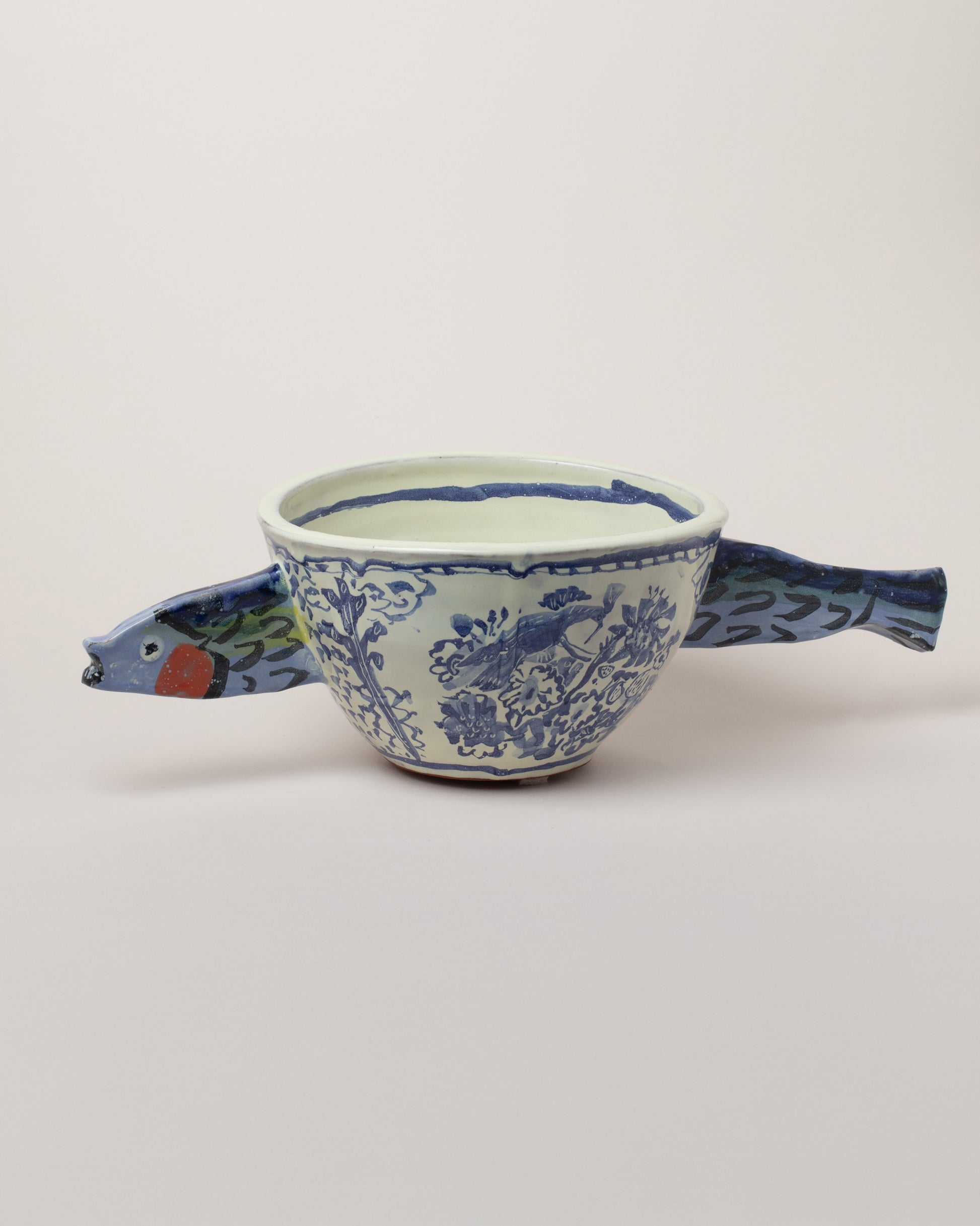 Maggie Boyd Sardine Swimming Through Delftware Bowl on light color background.