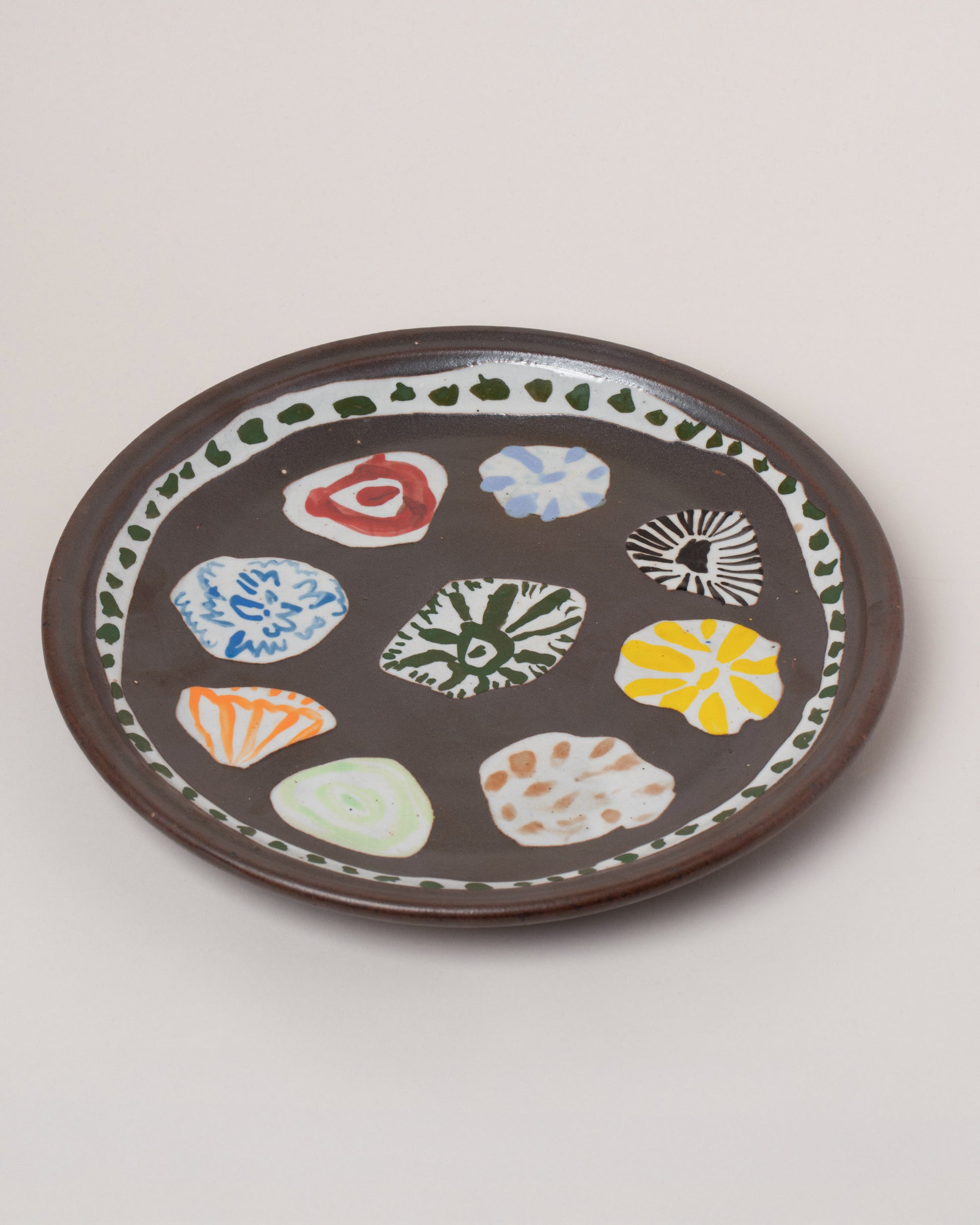 Maggie Boyd Tenmoku Petal Platter on light color background.