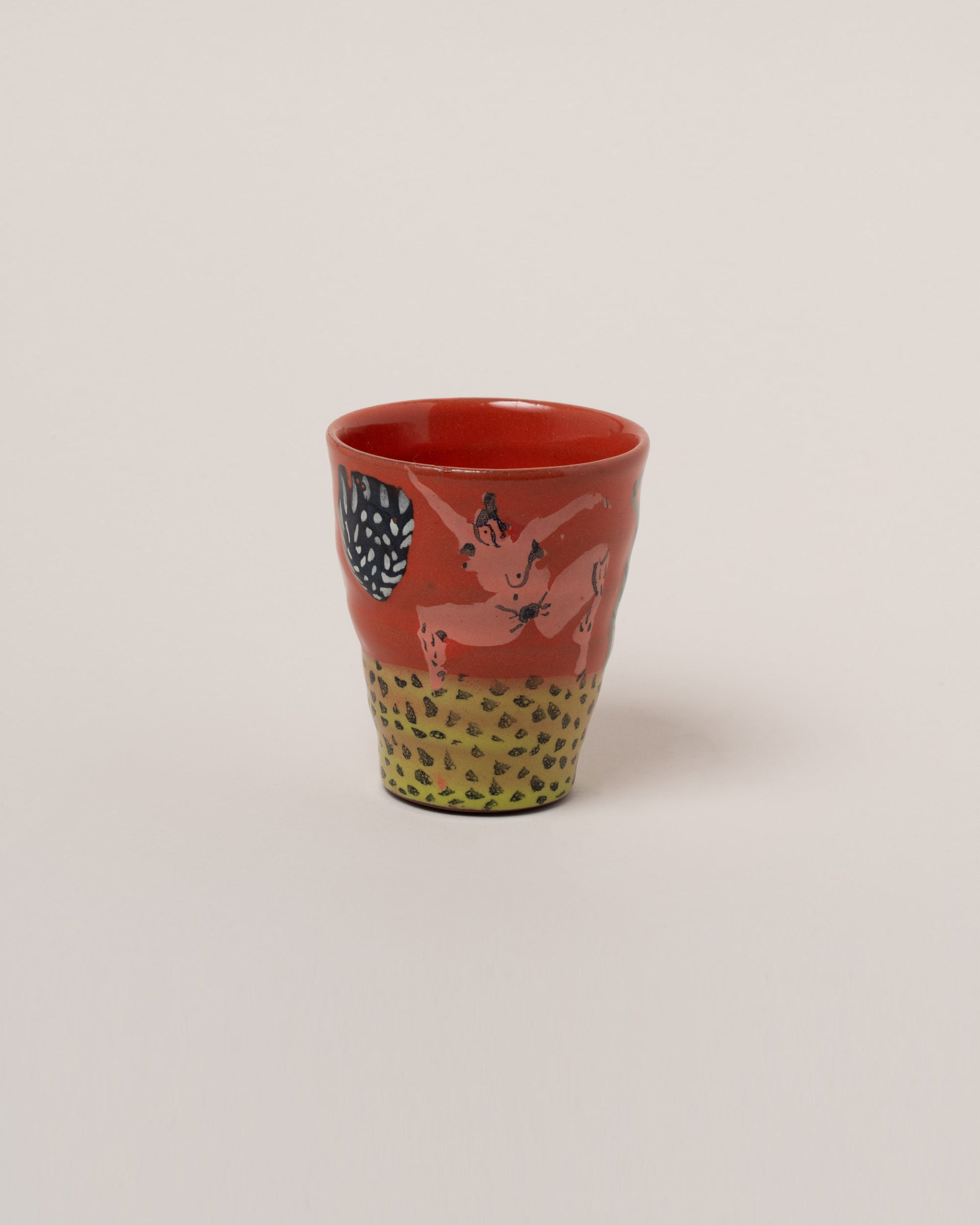 Maggie Boyd Two Red Figures On Grass Tumbler on light color background.