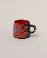 Maggie Boyd One Red Jestercore Mug on light color background.