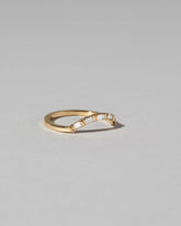 View from the side of the Gold Baguette Mini Curve Band on light color background.