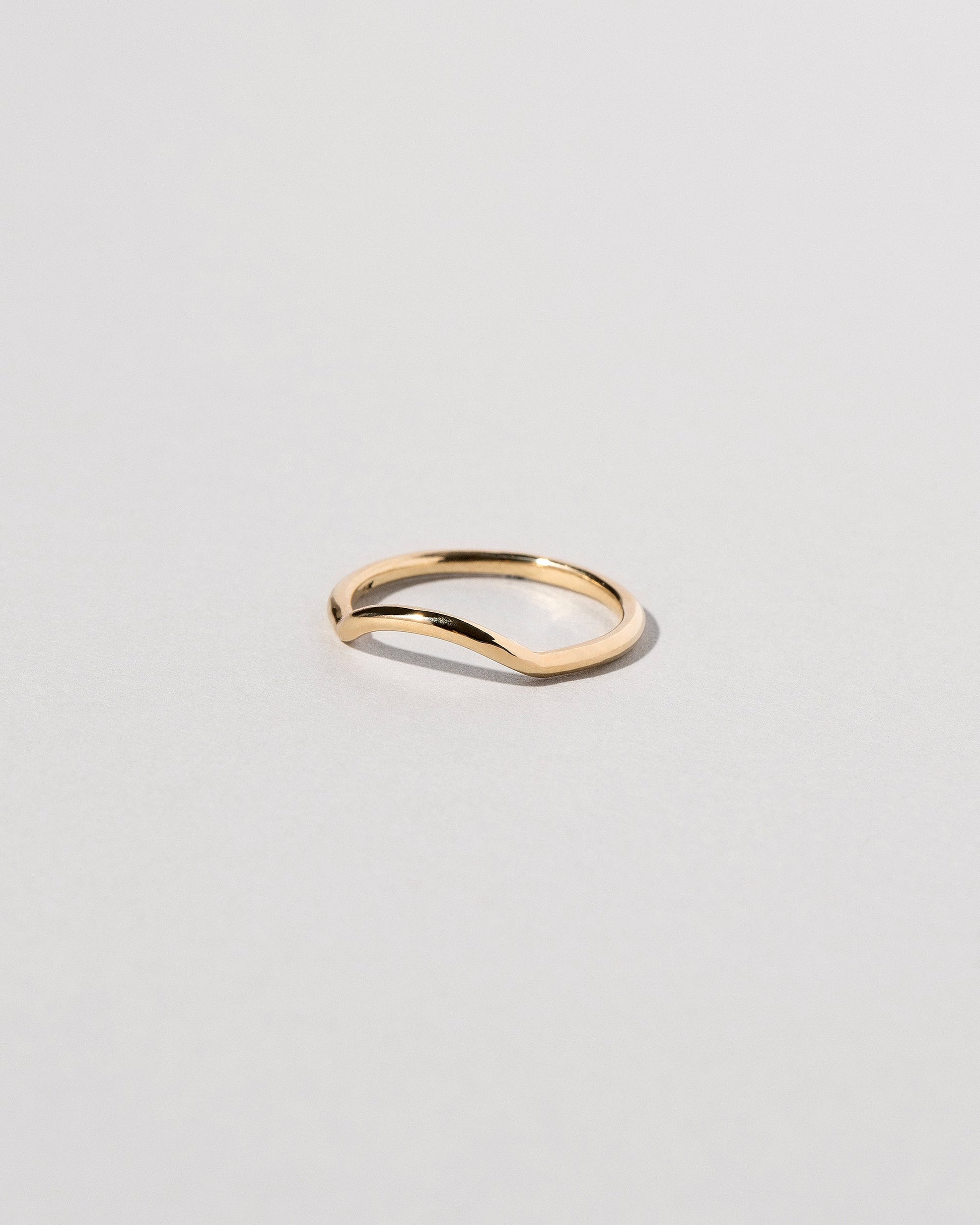 View from the side of the Gold Solid Round Wire Mini Curve Band on light color background.