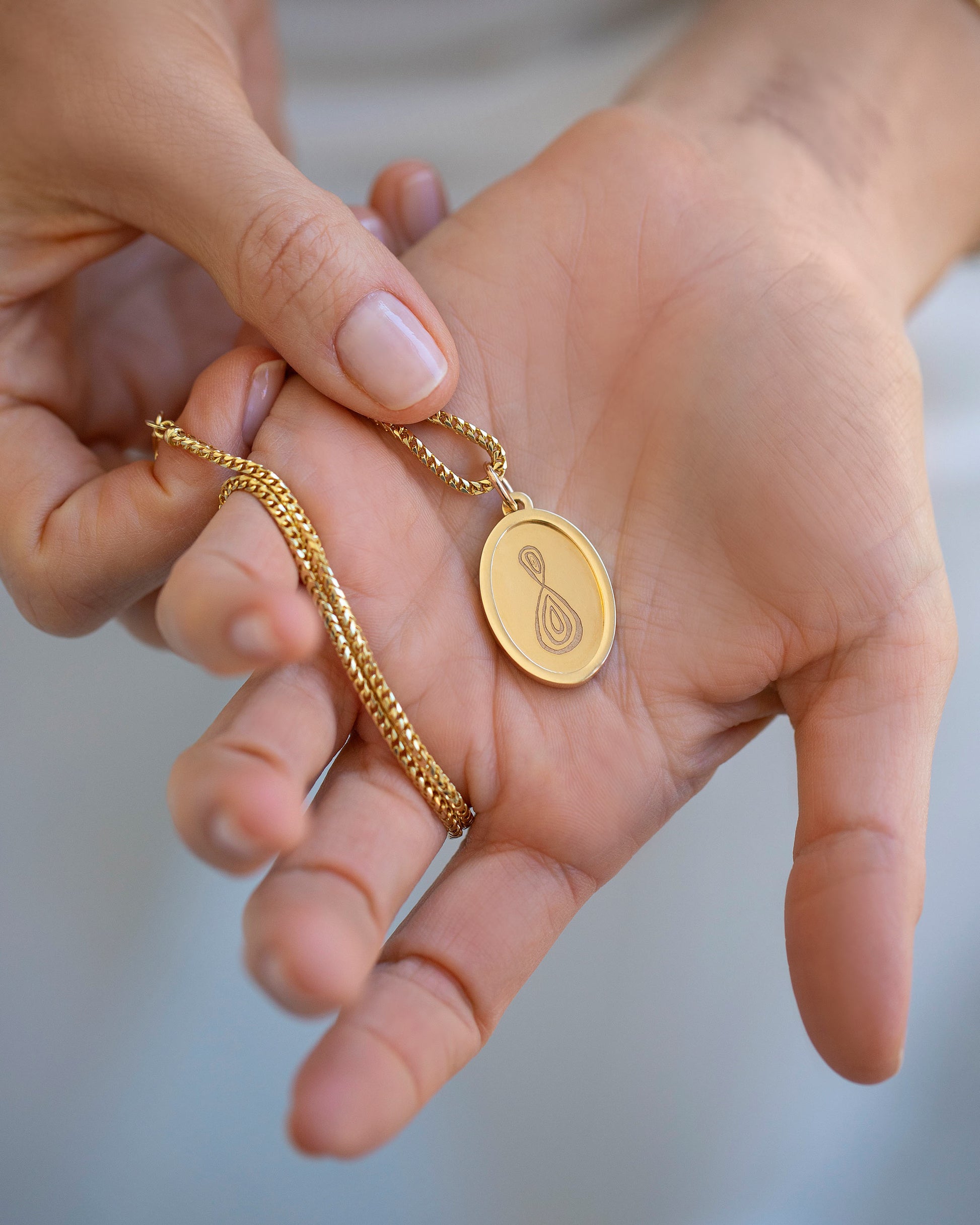 Finished Large Oval Memento Pendant in hand, paired with the Mociun 2mm 18" Ritual Chain Necklace. 