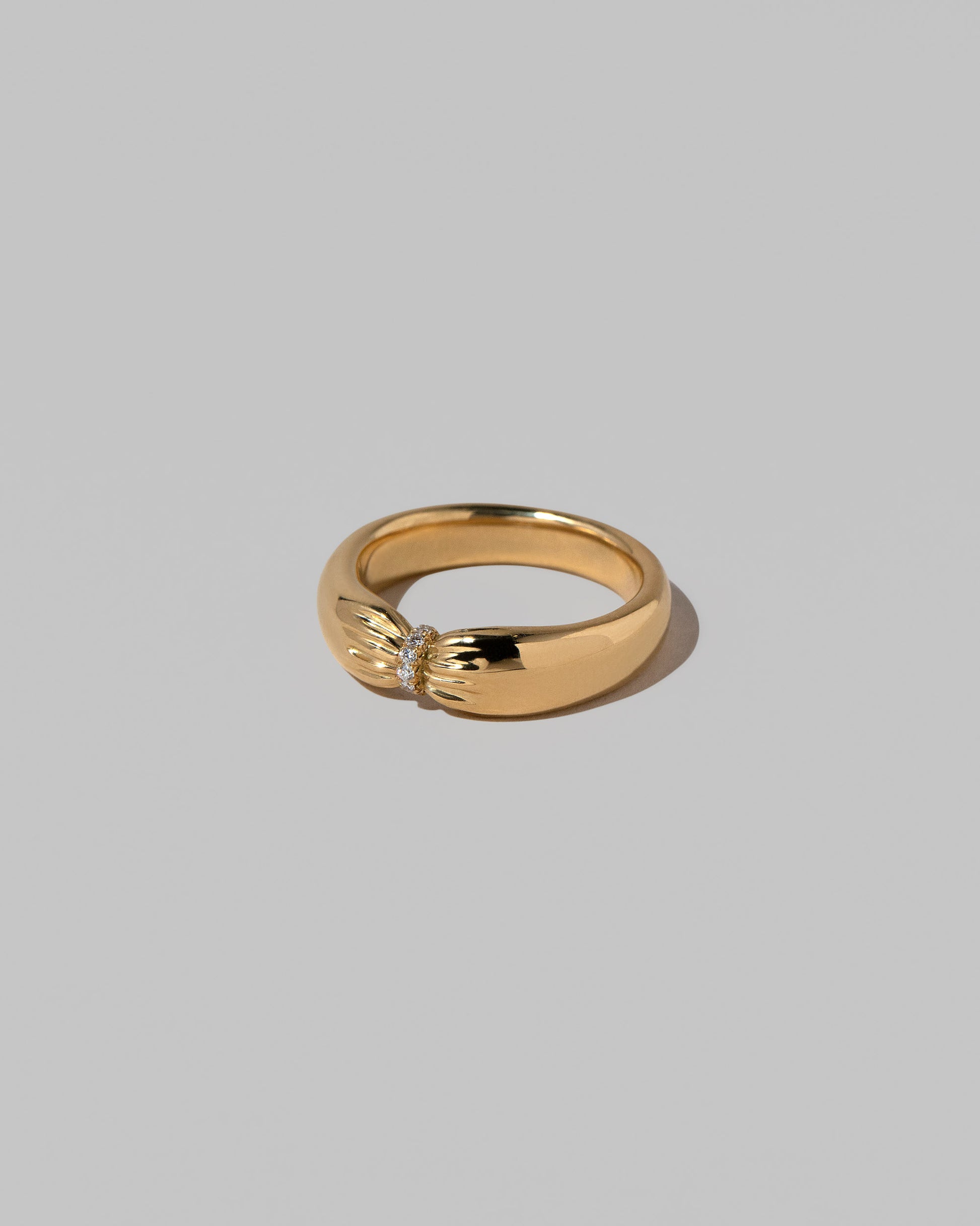 View from the side of the Gold Pavé Pinch Band on light color background.