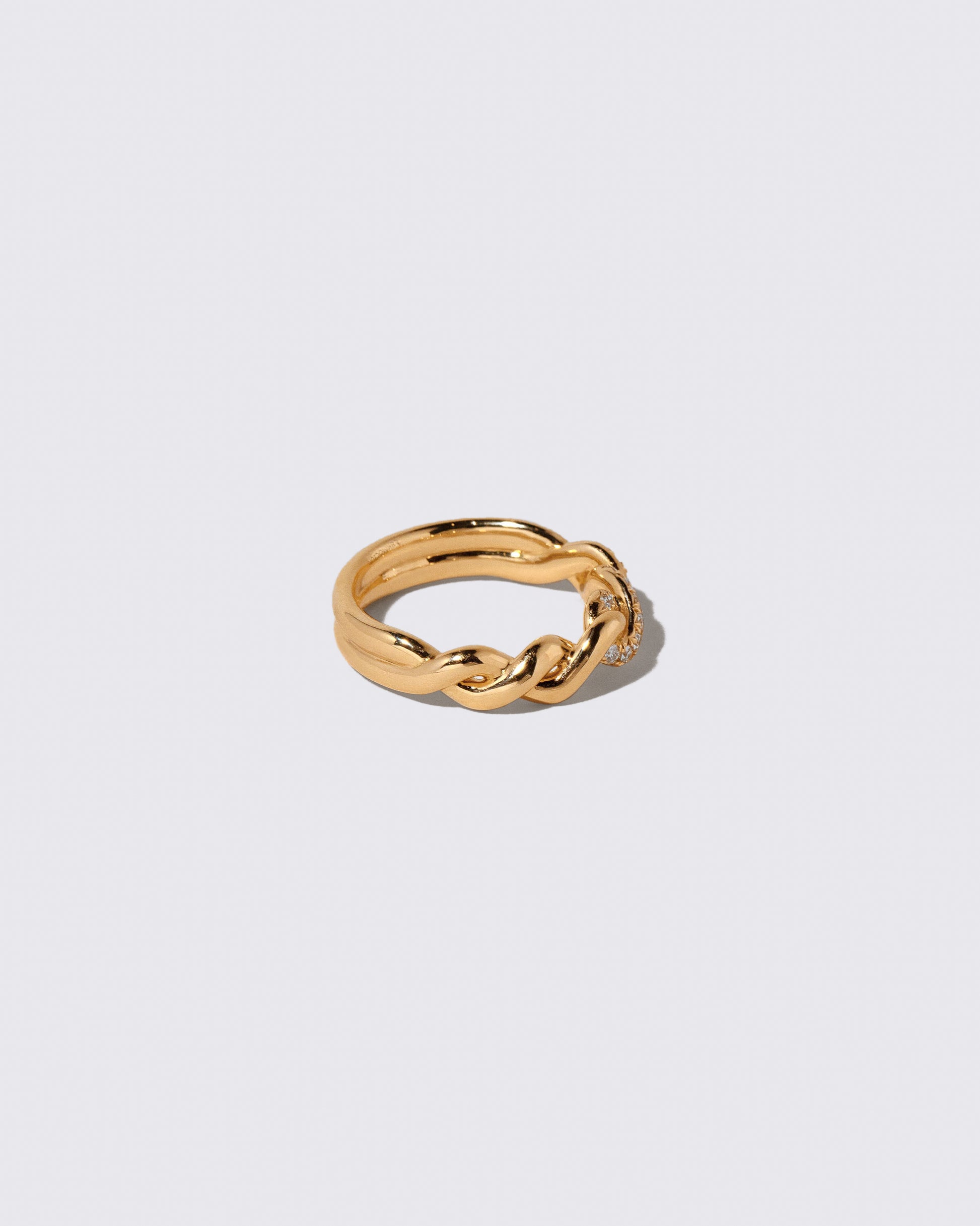 View from the side of the Gold Pavé Twist Band on light color background.