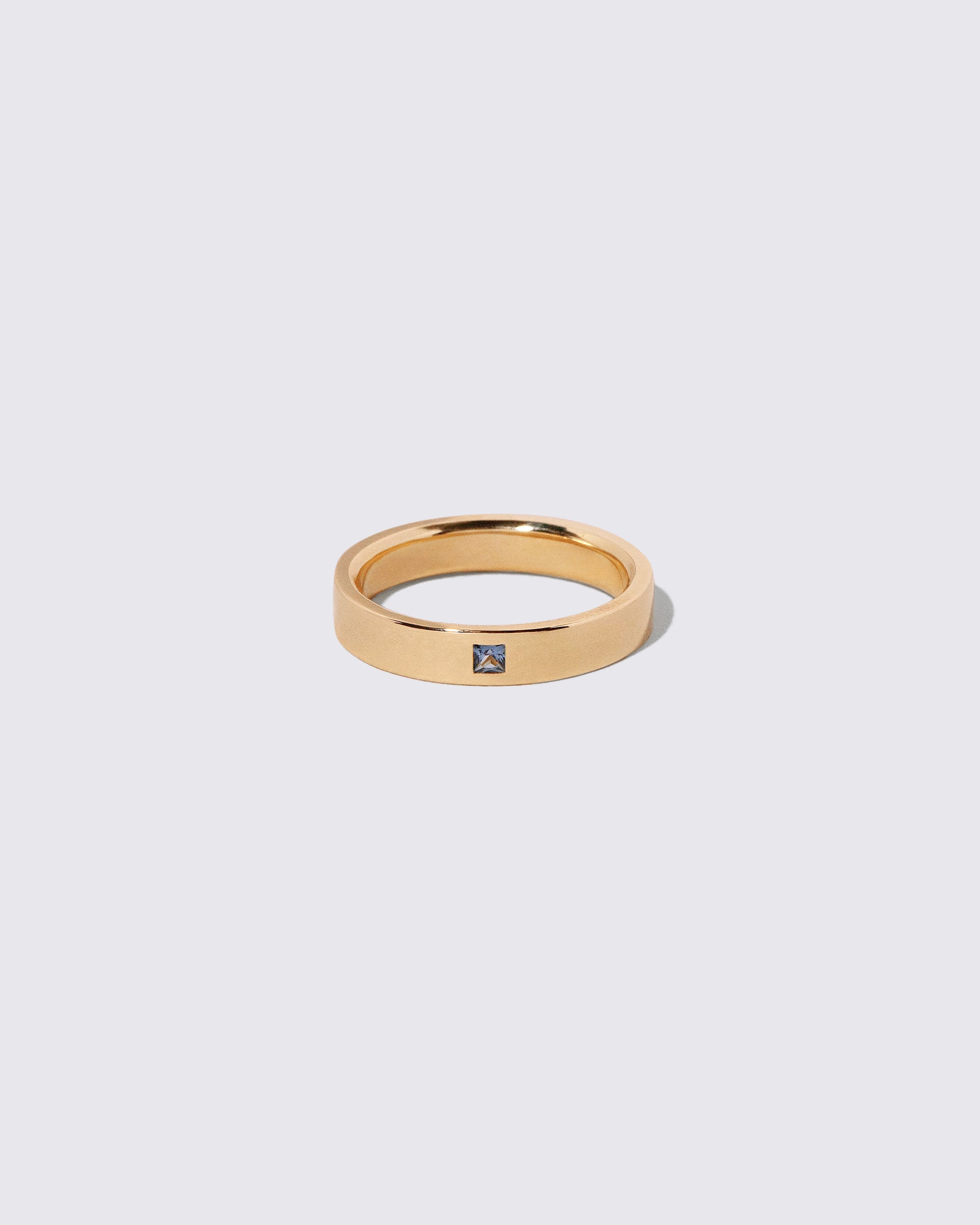 Gold Yogo Mine Cornflower Blue Sapphire 4mm Square Cut Piet Band on light color background.