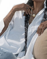 Styled image on model featuring the Grand Duality Medallion Pendant, Gold Butter Chain Necklace, Gold Infinity Openable Link, Infinity Openable Link Bracelet, Link Bracelet, Gold Pearl Openable Link Bracelet, Accumulation Bracelet and Tricolor Butter Chain Bracelet.