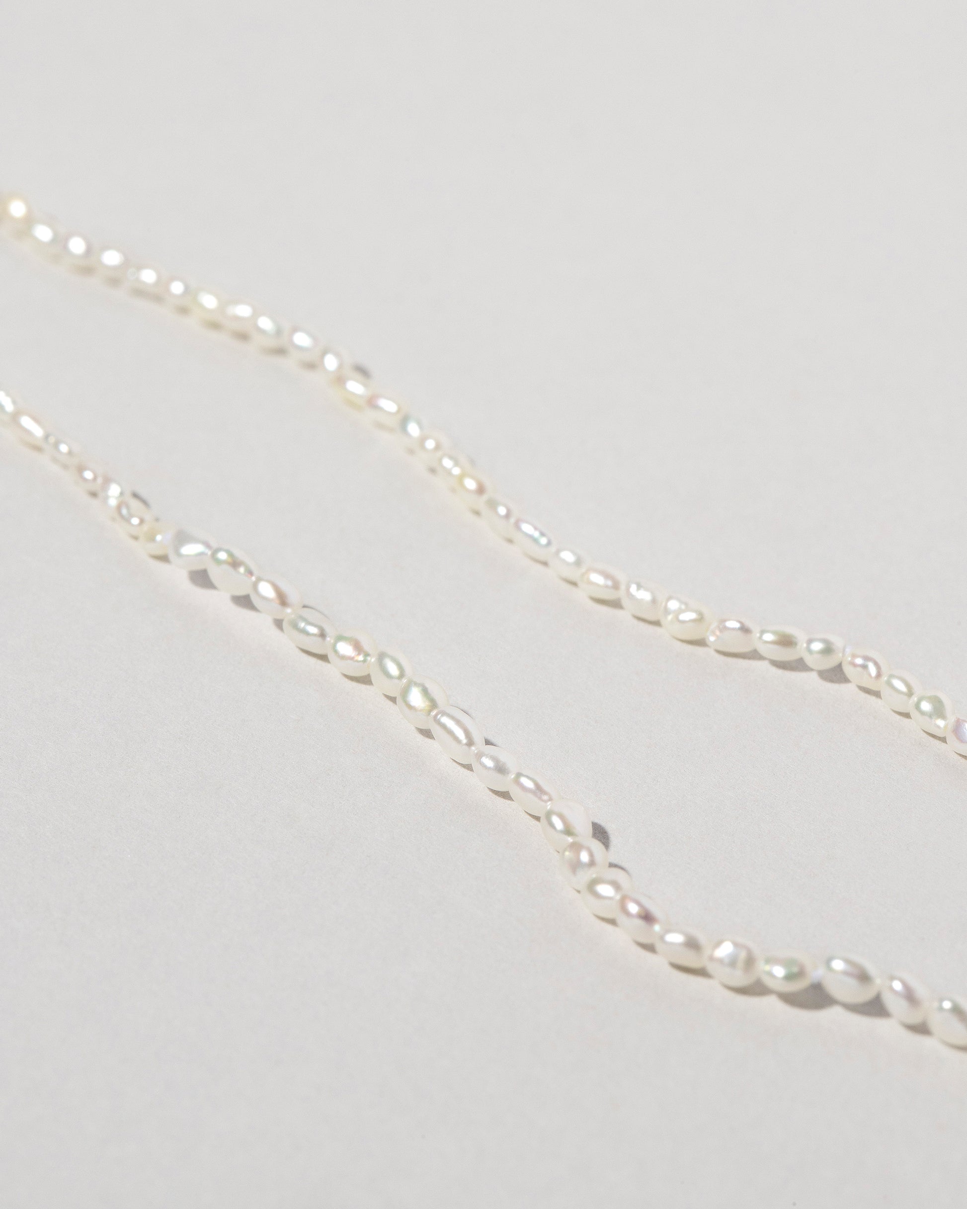 Closeup details of the White Oval Seed Pearl Bracelets on light color background.