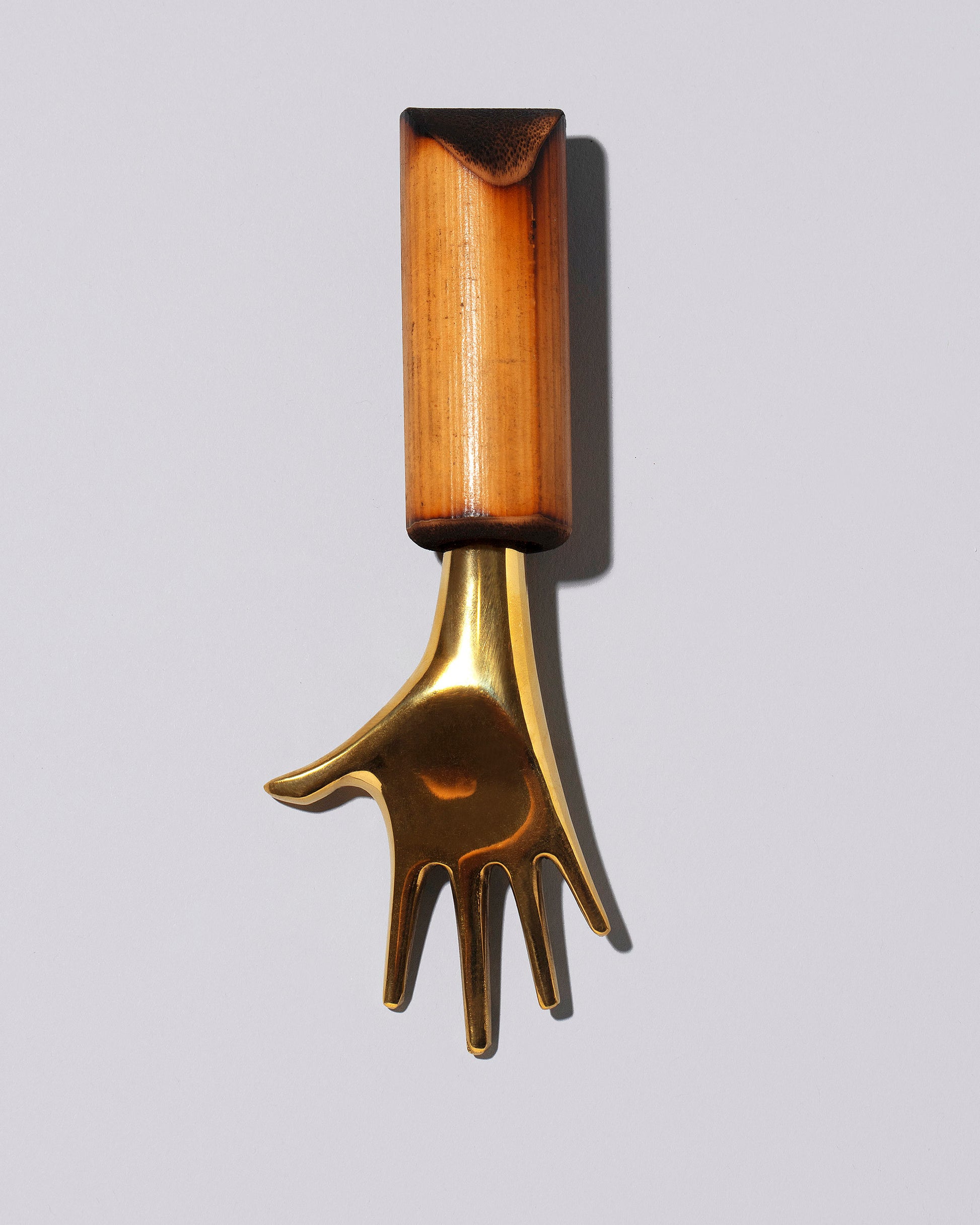 Closeup view of the Carl Auböck Brass Hand Corkscrew on light color background.