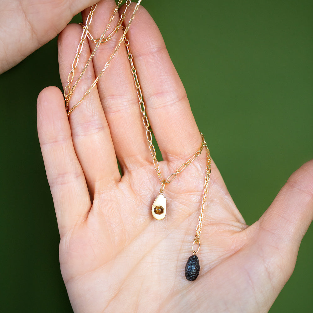 product_details::Hot Dog Chain Necklace with the 'pitted' Halved Avocado Charm and Petite Diamond Cut Chain Necklace with the 'pitless' Halved Avocado Charm on model.