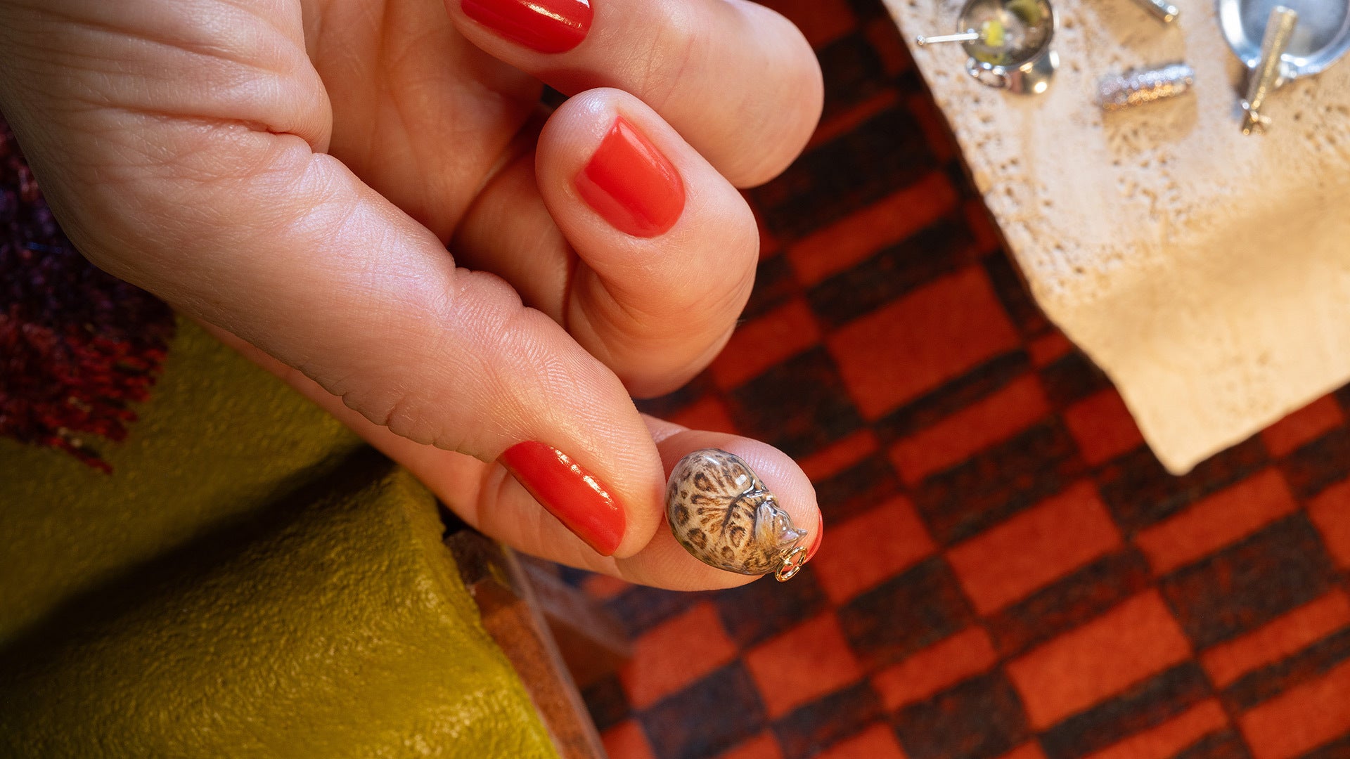 Styled image of the Bengal Curled-Up Cat Charm in hand.