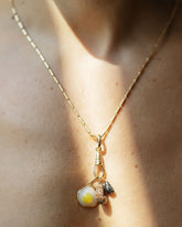 Gold Butter Chain Necklace worn with a Gold Oval Openable Link clipped to the Gold Grid Swivel Charm Holder styling a Bengal Curled-Up Cat Charm, Halved Avocado Charm and Fried Egg Pendant on model.