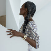 product_details::Styled image on model featuring the Blue Sapphire Gusher Charm Huggie Hoop Earrings, a Double Drop Ring the Gold 5mm Ripple Band on hand, a Link Bracelet and Gold Pearl Openable Link Bracelet on wrist and the Infinity Openable Link Necklace, Link Necklace and Petite Link Necklace layered on neck.